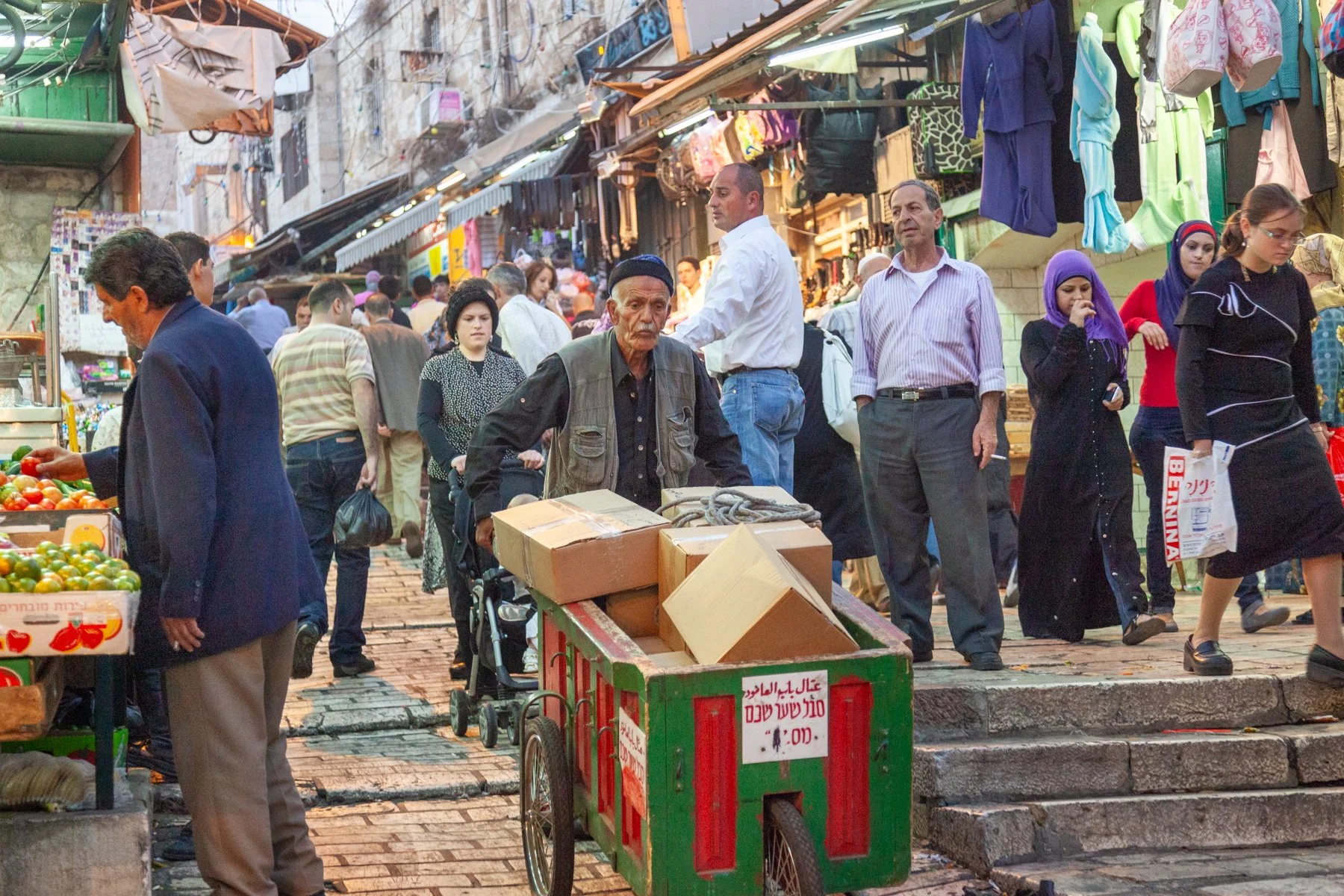 Man pulling a handcart through a busy market street in Jerusalem’s Old City.