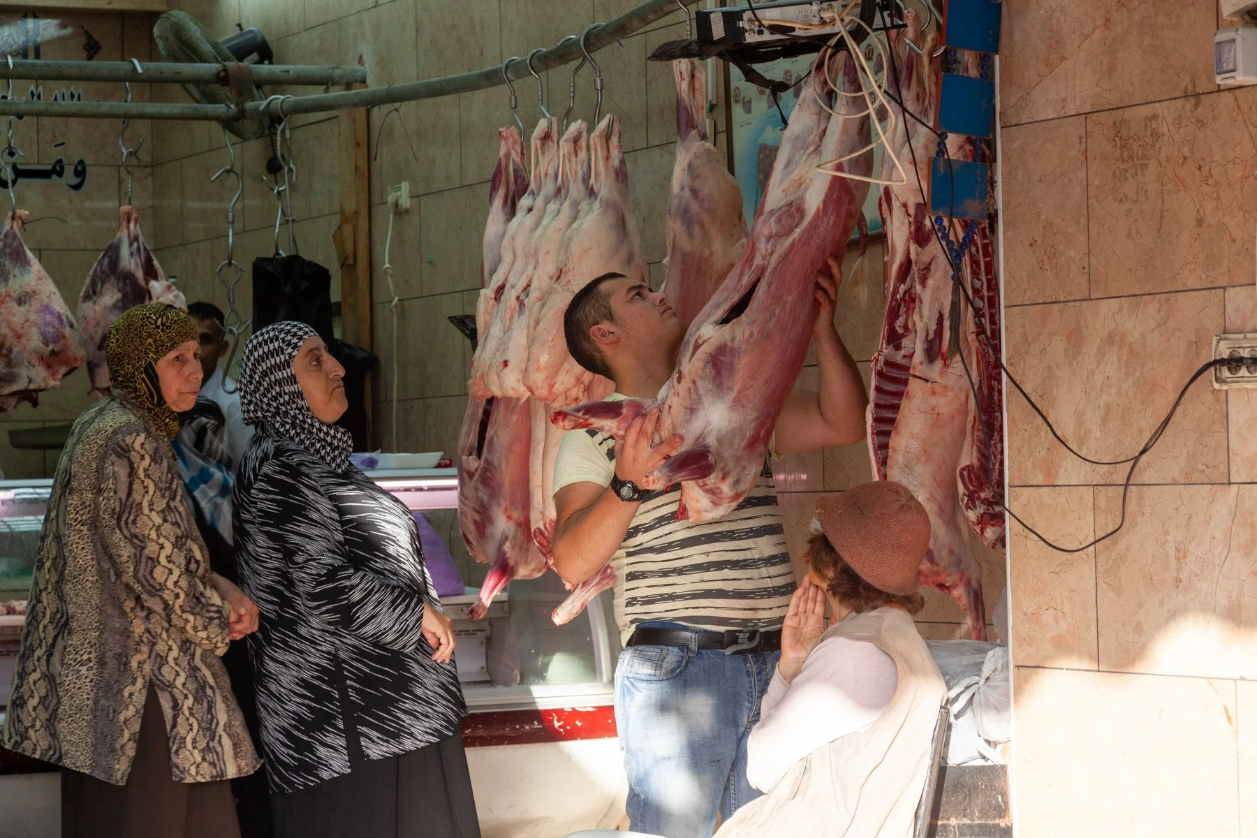 Butcher hanging fresh meat in a market shop in Jerusalem.