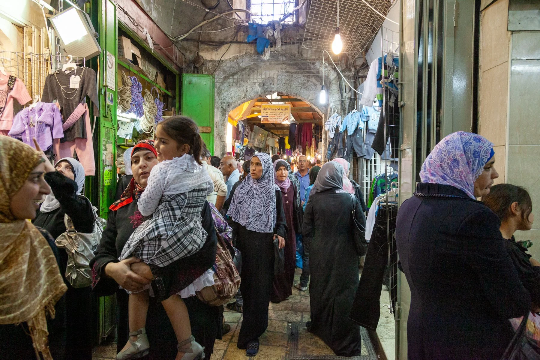 Women and families walking through a crowded market street in Jerusalem’s Old City.
