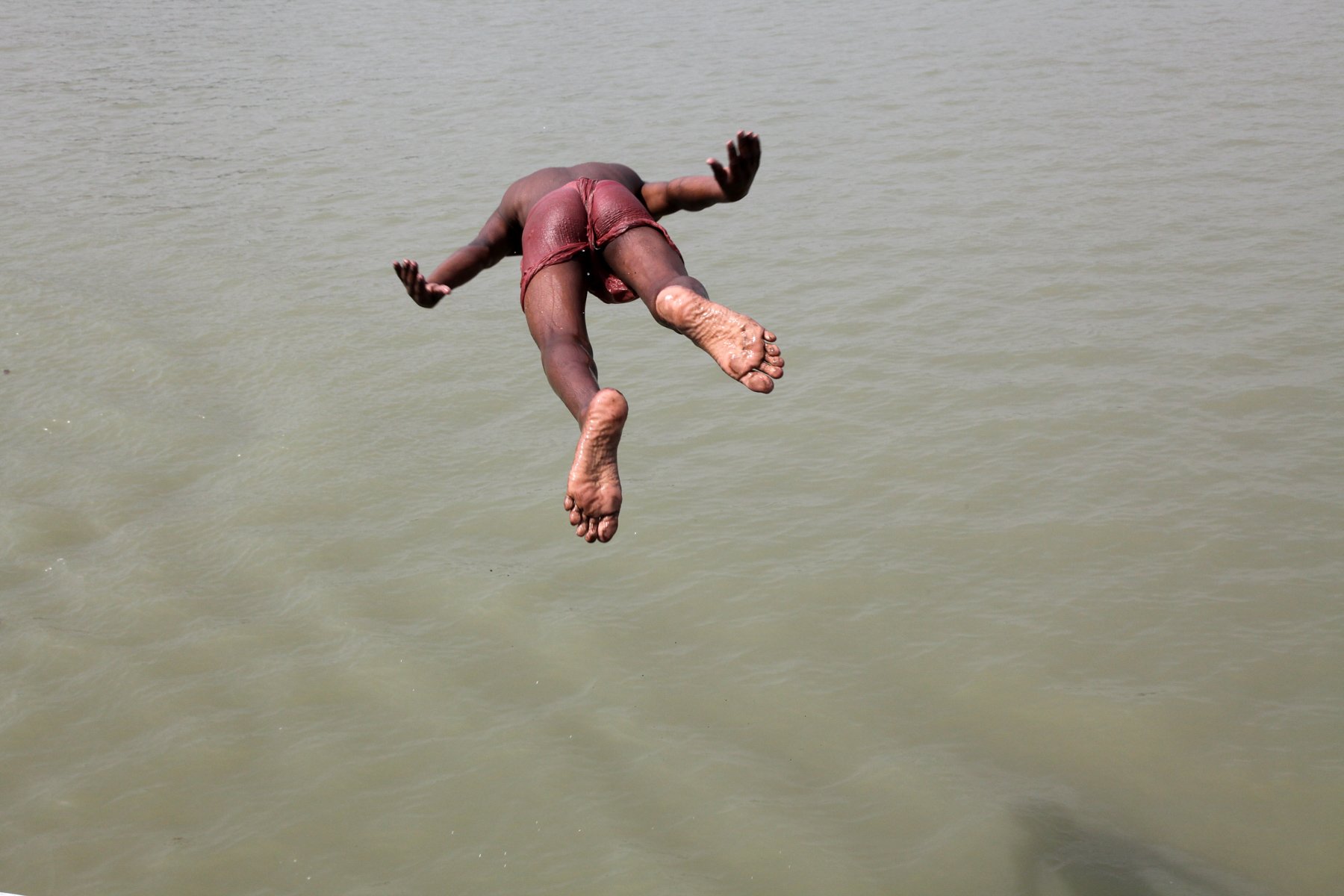 A boy is captured mid-air while diving into the Hooghly River in Kolkata, West Bengal, India. Swimming and diving in the river are a familiar part of everyday life for many local children during the hot season. April 2009.