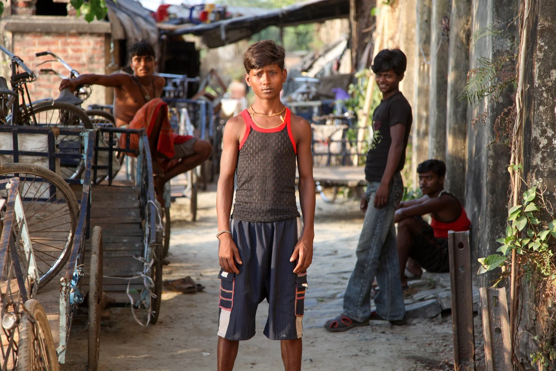 A young man stands in a narrow lane of a neighbourhood along the Hooghly River in Kolkata, West Bengal, India. The portrait documents everyday life in one of the communities that have developed close to the city’s historic waterfront.