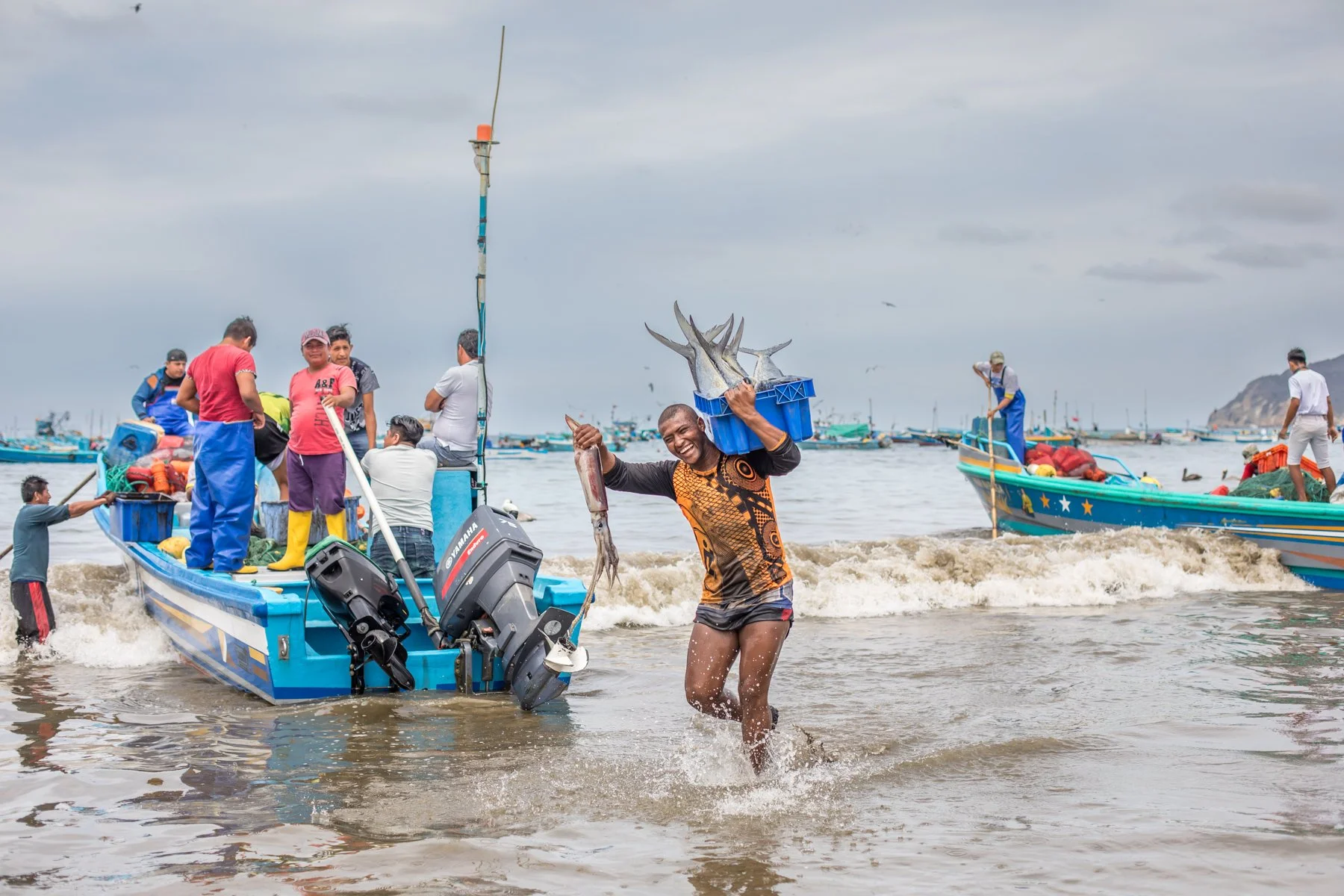 An artisanal fisherman carries freshly landed fish through the surf after returning to the beach at Puerto López. The image documents the traditional landing of the daily catch on Ecuador’s Pacific coast.