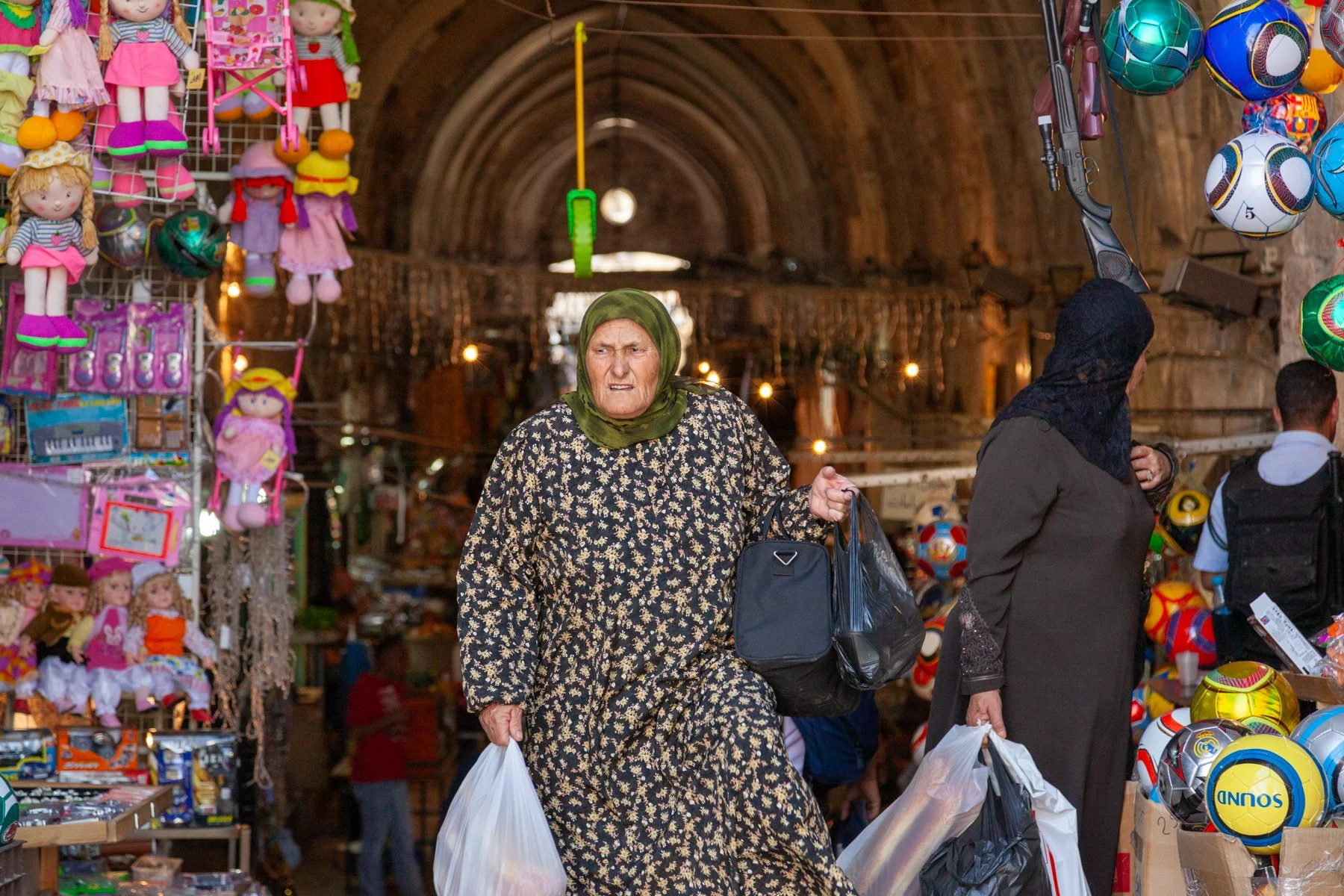 Elderly woman carrying shopping bags in a narrow street in Jerusalem’s Old City.