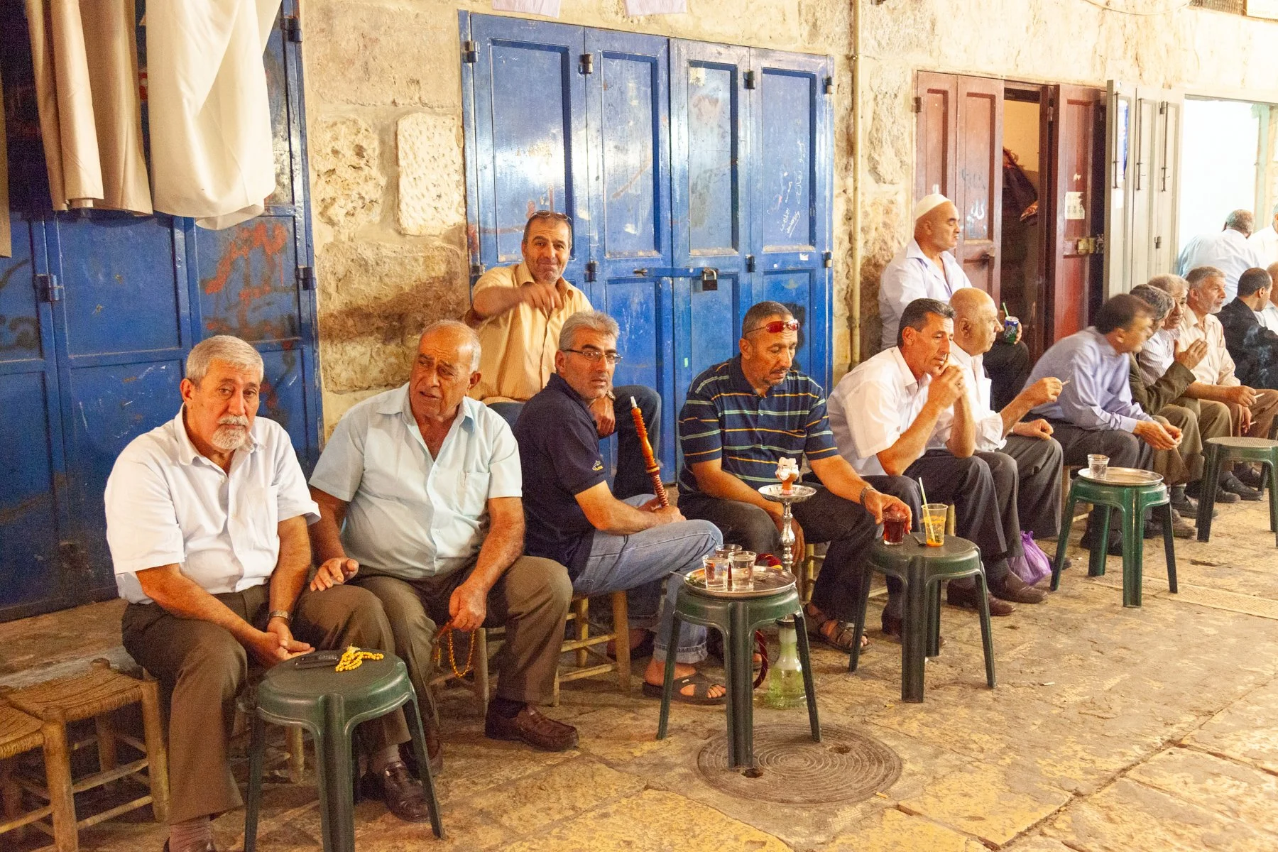 Men sitting and standing outside a small café in Jerusalem’s Old City.