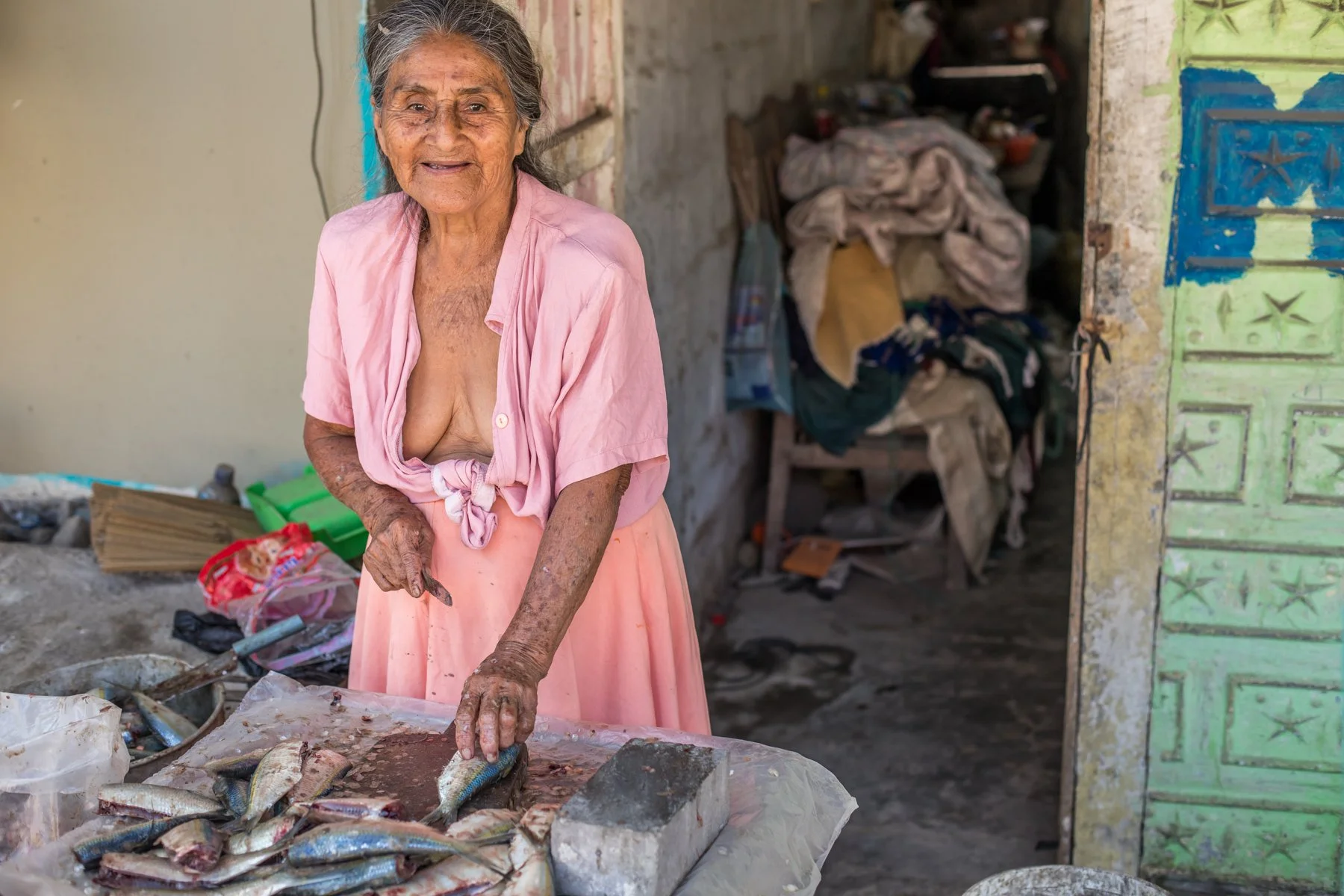 An elderly fish vendor pauses while preparing freshly caught fish at her small stall in Puerto López, Ecuador. Her portrait reflects the people whose daily work sustains the traditional artisanal fishing community on Ecuador’s Pacific coast.