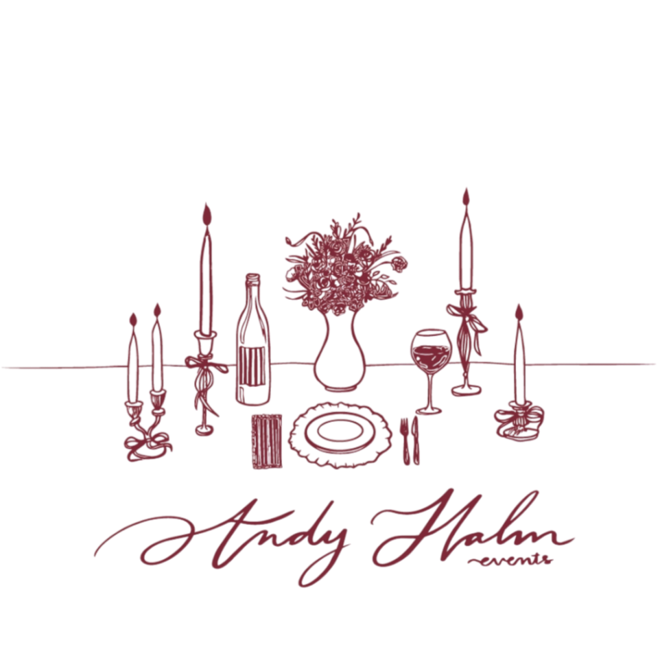 A decorative table setting with candles, a bouquet of flowers, a wine glass, plates, and a the "Andy Hahn Events" name.