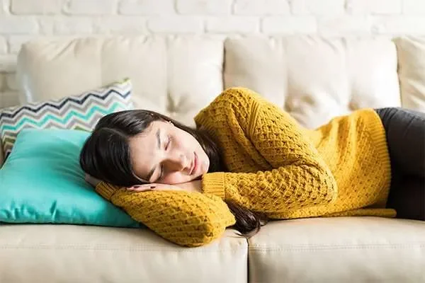 Woman napping on a sofa in the afternoon – the siesta and biphasic sleep