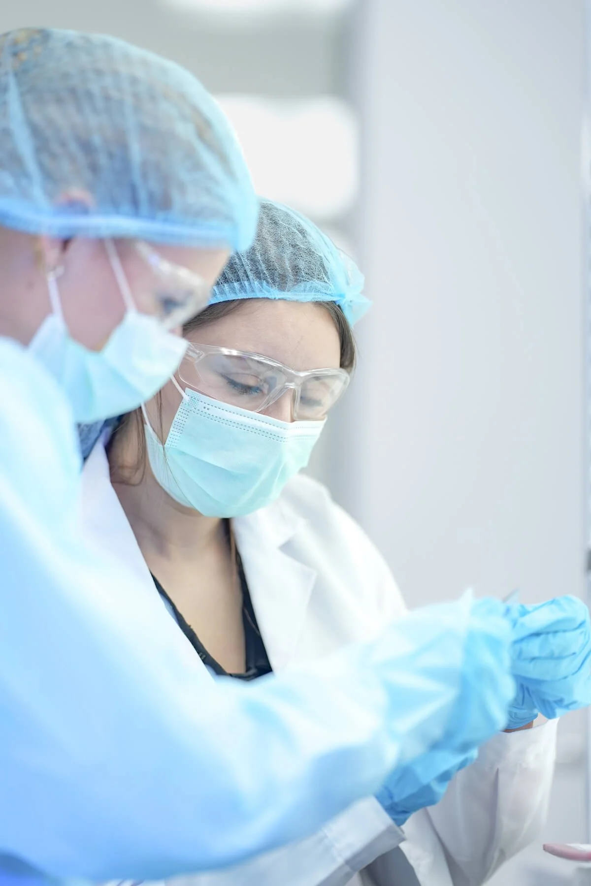 Two scientists in a clean room in hair nets and masks and gloves