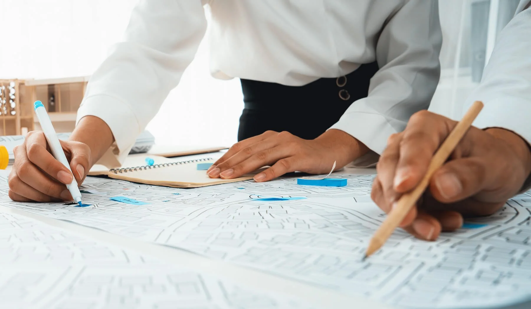 Architect and Engineer's hands pointing to a site plan with pencils