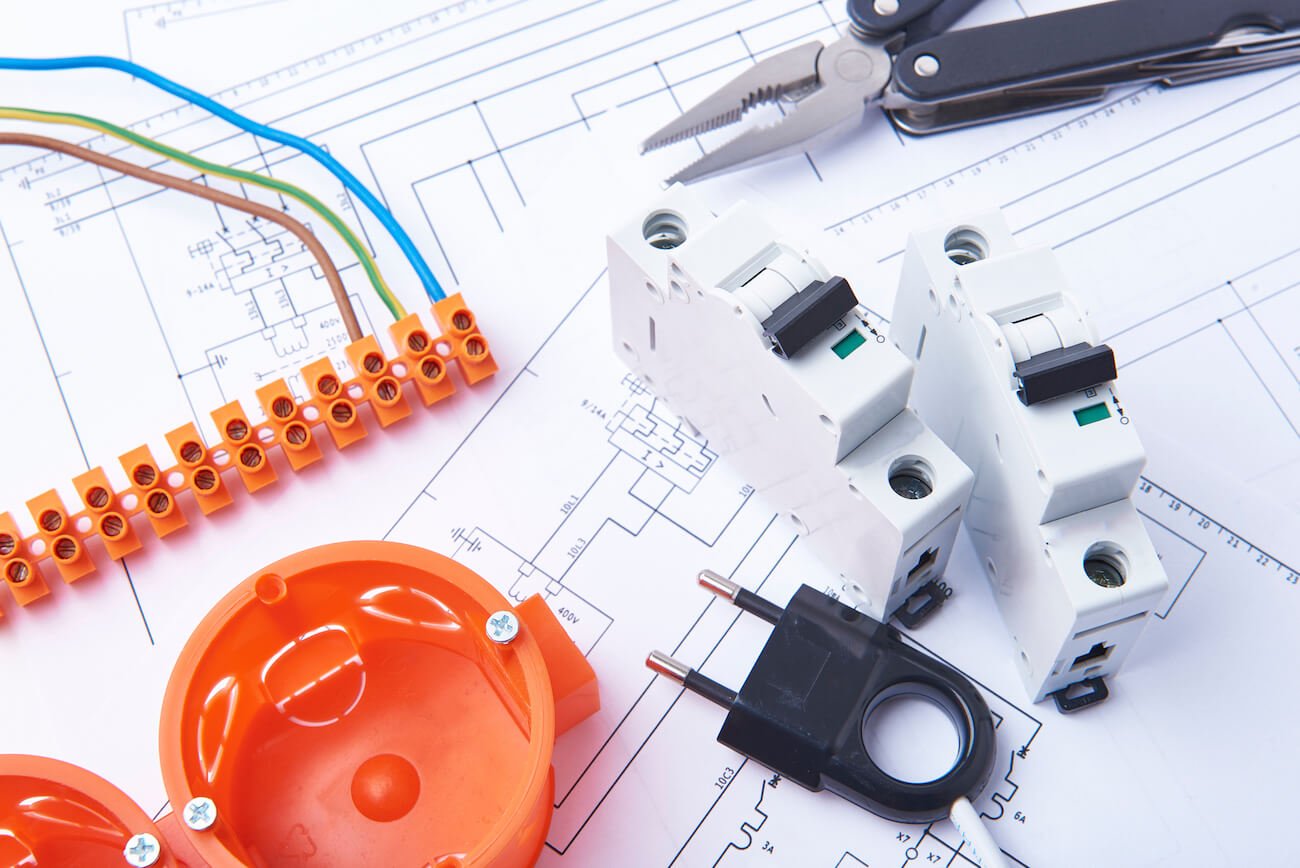 Electrical connectors with wires, junction box and different materials used for jobs in electricity. Many tools lying on diagrams.