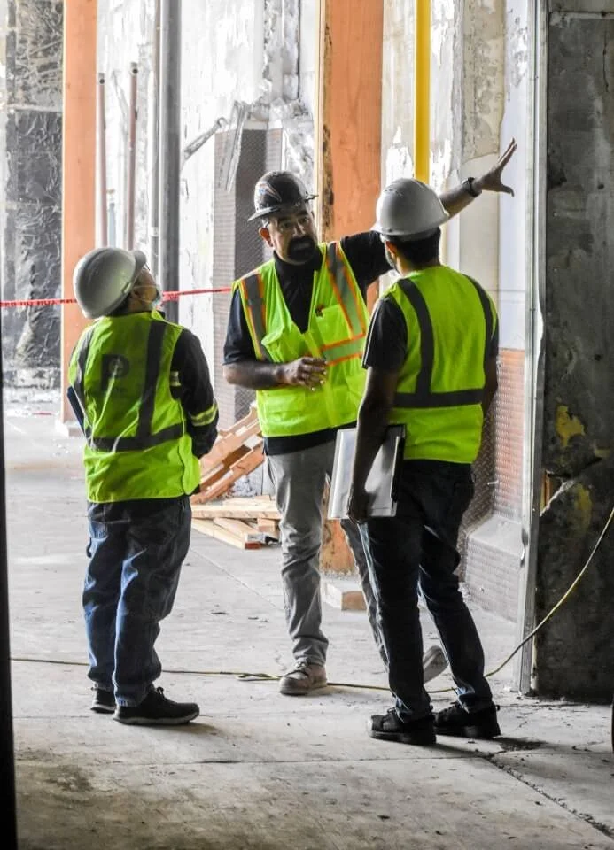 Three team members from Plump Engineering discussing structural engineering on an old building
