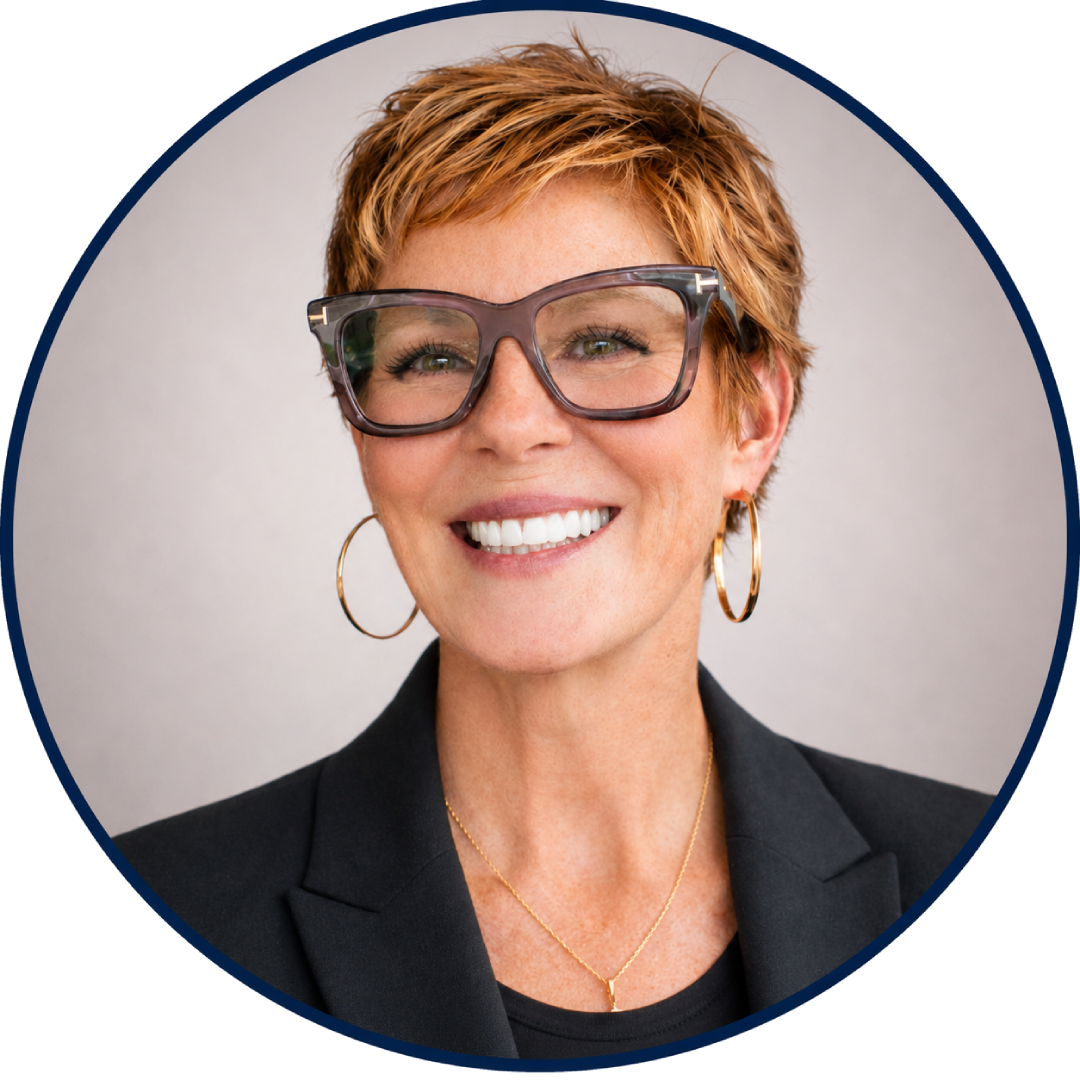 Smiling woman with short red hair, large glasses, hoop earrings, and a black blazer