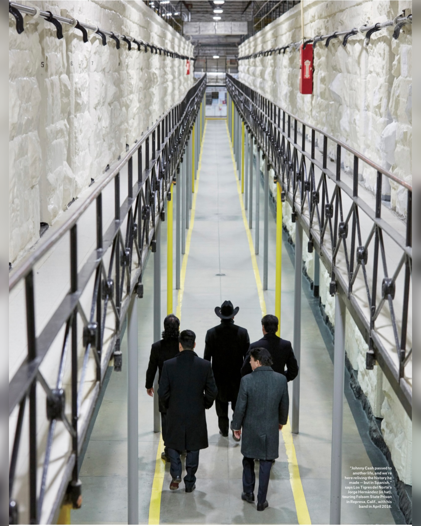 A group of men walking through an industrial space with large blocks of white material on either side, possibly in a factory or storage facility.