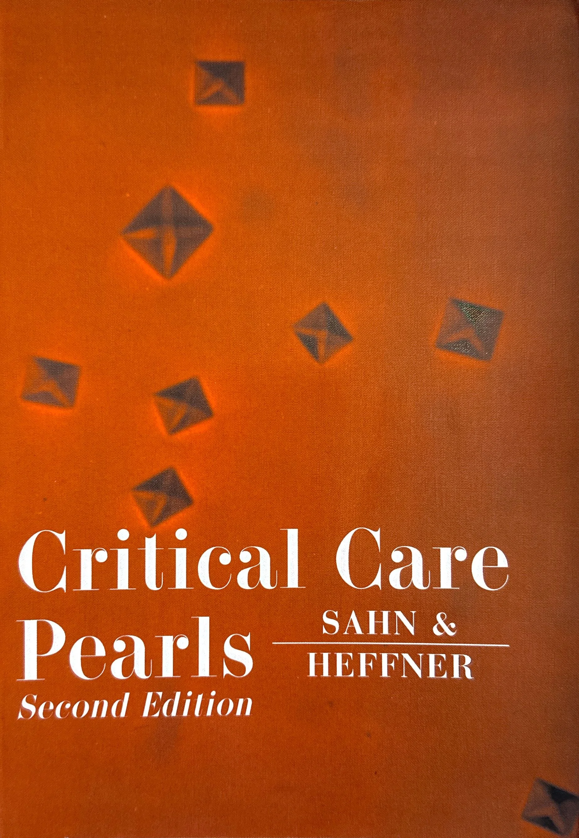 Cover of a book titled 'Critical Care Pearls' by Sahn and Hefner, second edition, with an orange background and black decorative symbols.