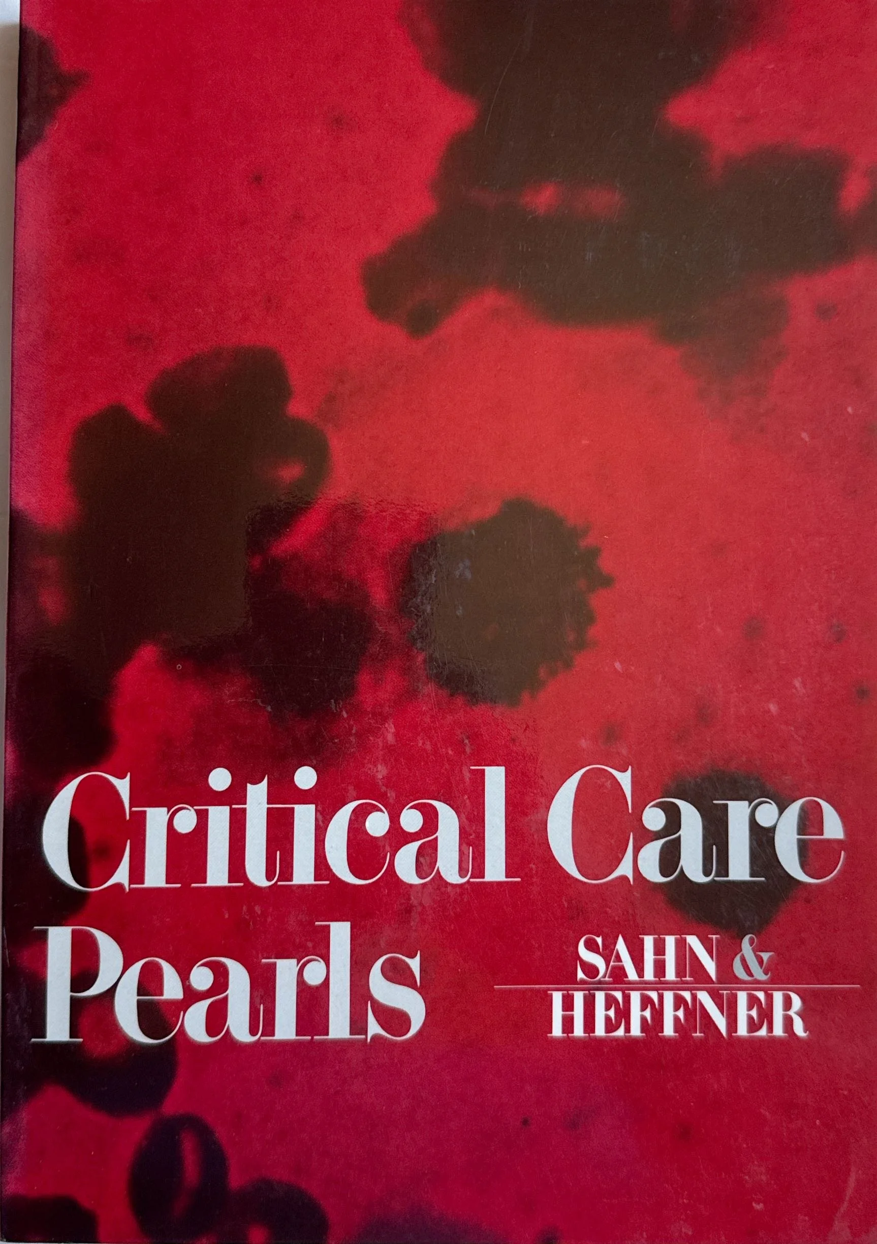 Close-up image of a book cover titled "Critical Care Pearls" by Sahn and Hefner, with a red background and black ink blotches that resemble flowers or abstract shapes.