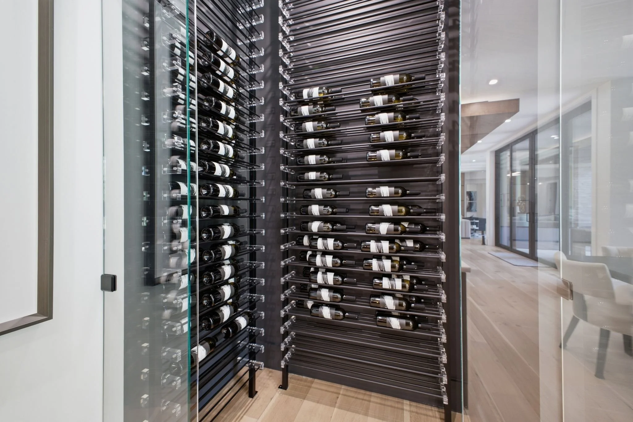 Wine bottles stored on metal racks inside a climate-controlled wine cellar or wine storage room.