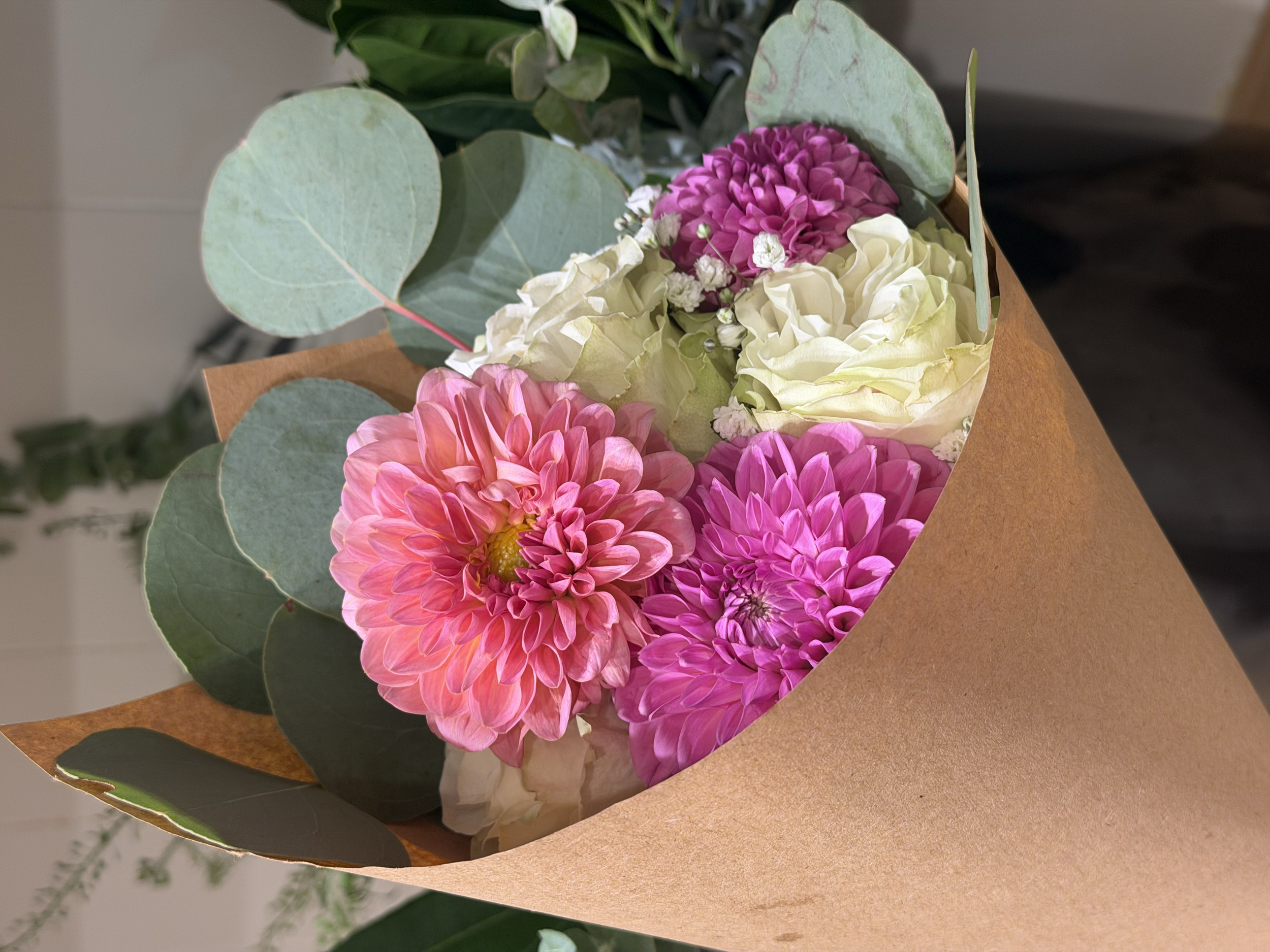 Close-up of a bouquet of pink and white flowers wrapped in brown paper.