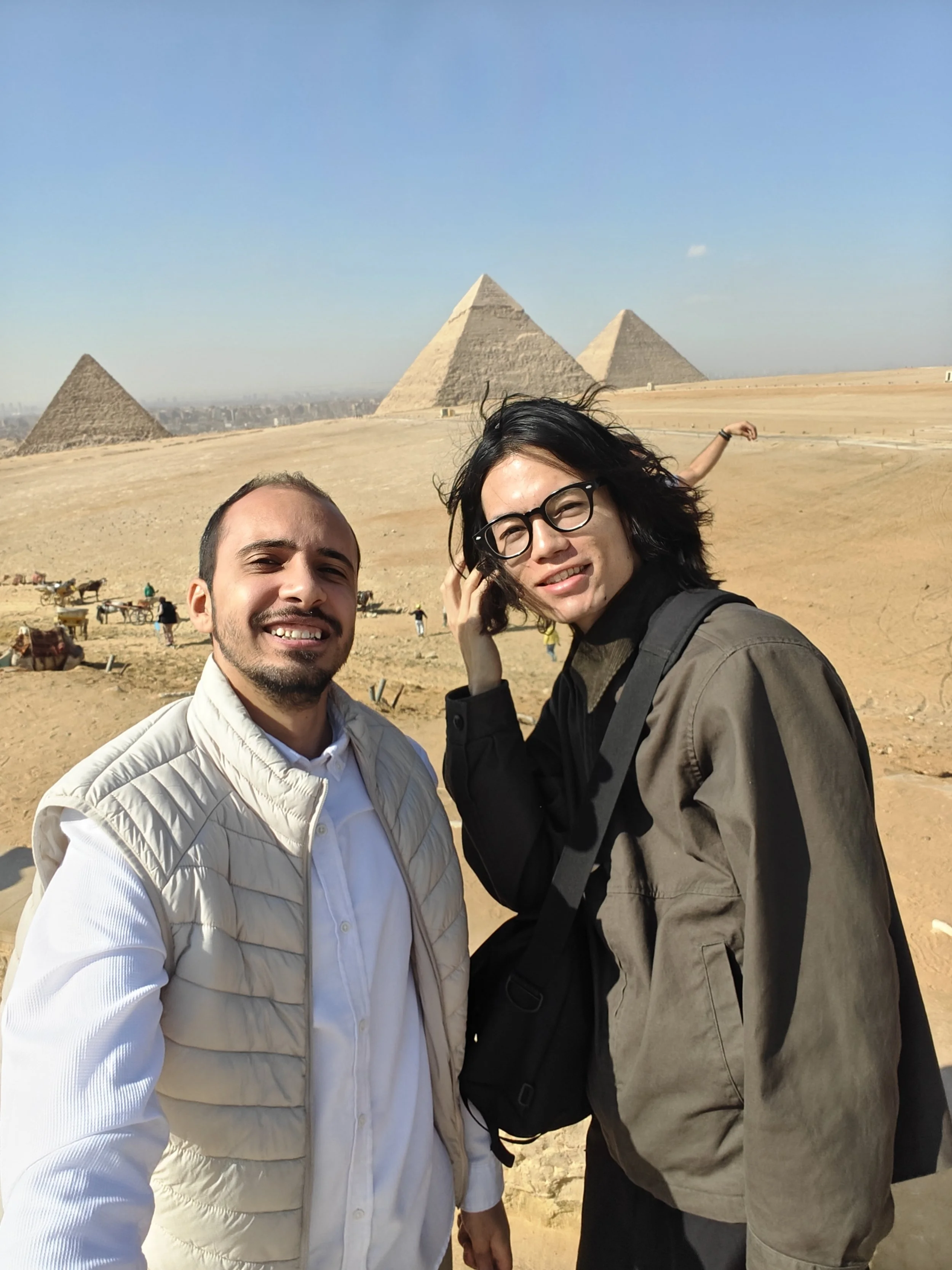 Two people taking a selfie in front of the pyramids in Egypt.