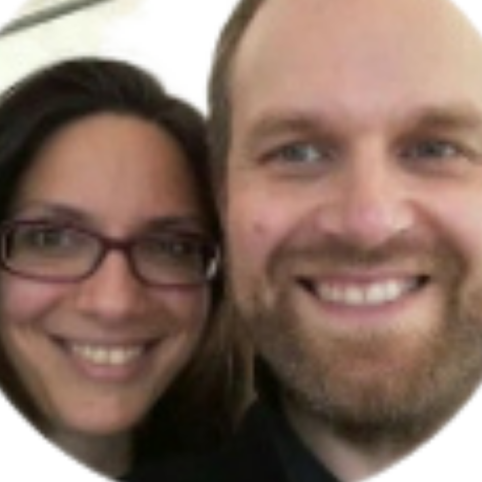 Close-up of a smiling woman with glasses and man with a beard smiling.