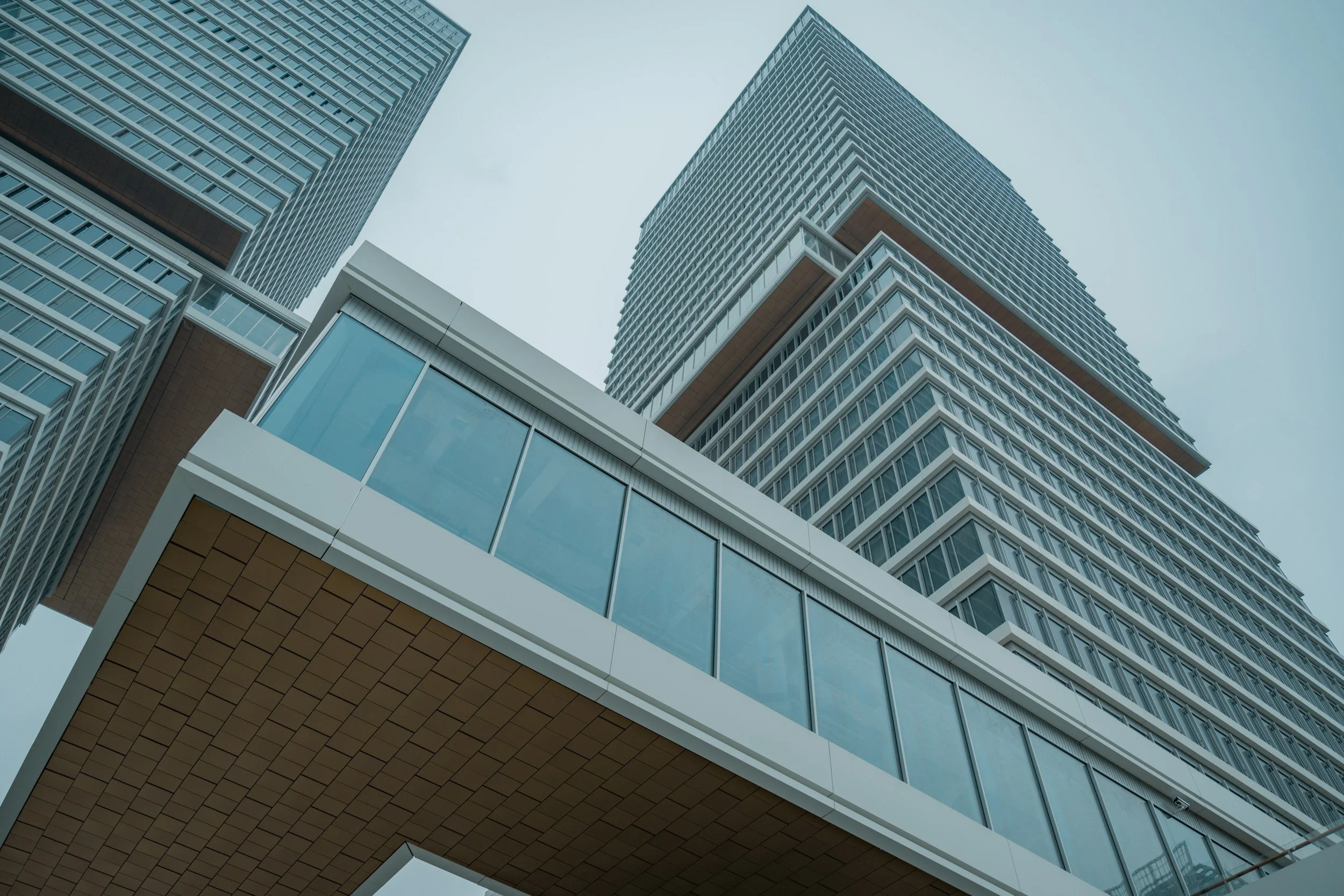 Low-angle view of modern high-rise glass and steel skyscrapers against a cloudy sky.