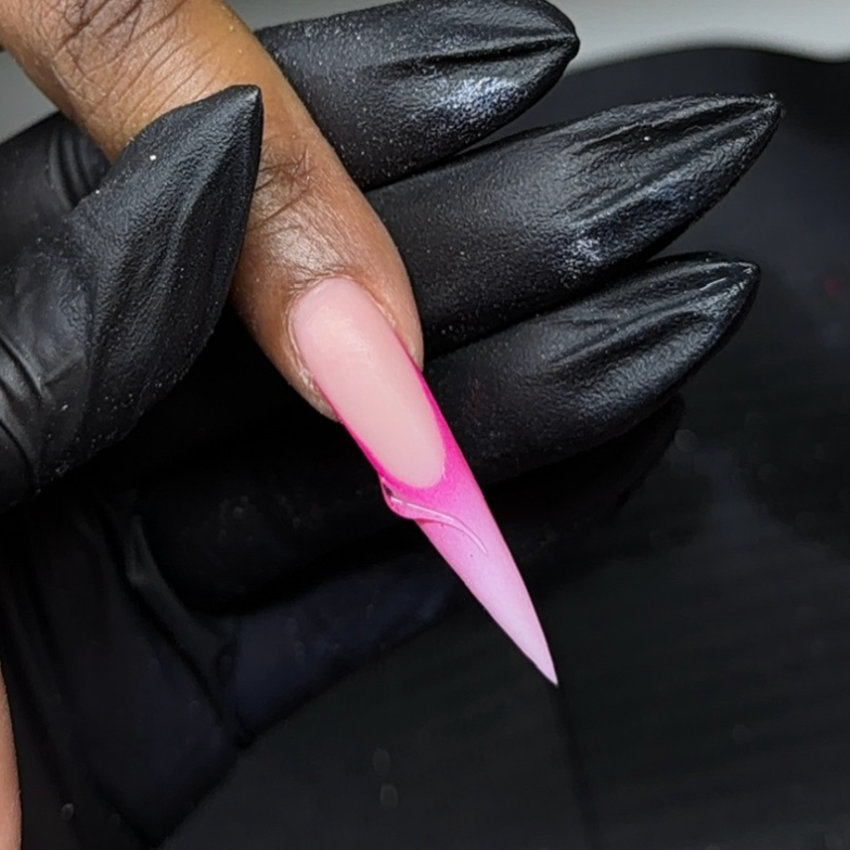 Close-up of a person's finger with long, pointed, pink acrylic nail, held by a hand wearing a black glove.