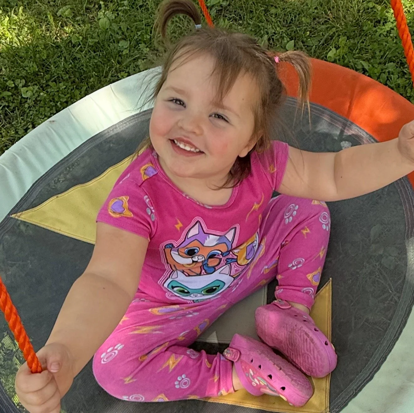Bella Grace smiles up from a swing down at Mimi & Pop's house, capturing the joy, innocence, and childlike faith that continue to inspire the Believe Like Bella ministry.
