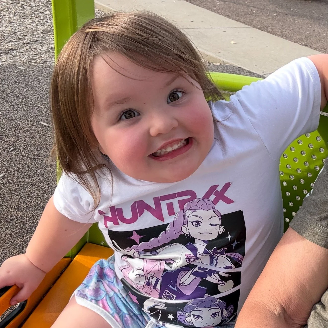 Bella Grace smiling while wearing a white Huntrix shirt, capturing the warmth, joy, and childlike faith that continue to inspire the Believe Like Bella ministry.