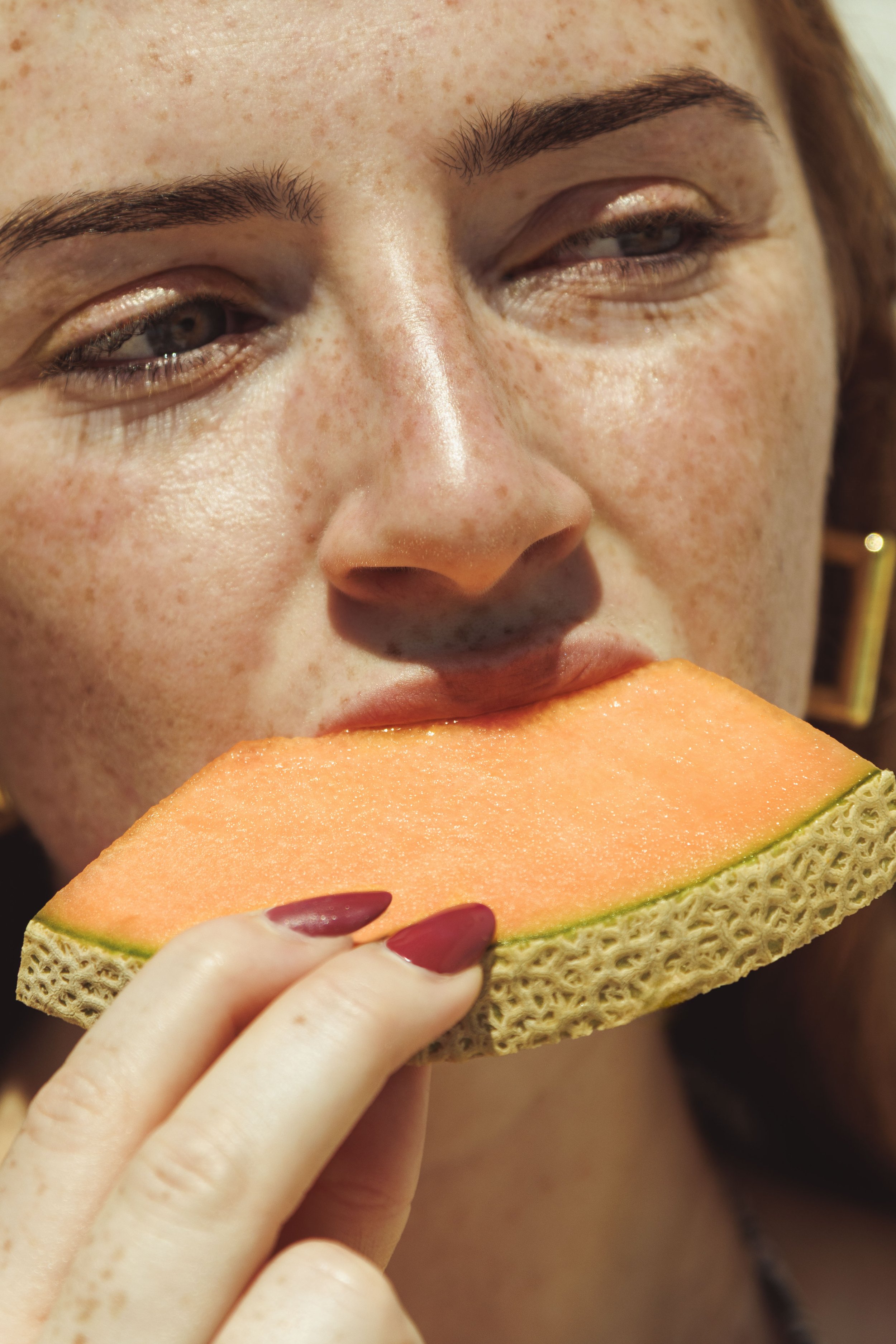 Commercial lifestyle portrait of a woman eating melon in the Los Angeles, California sun.