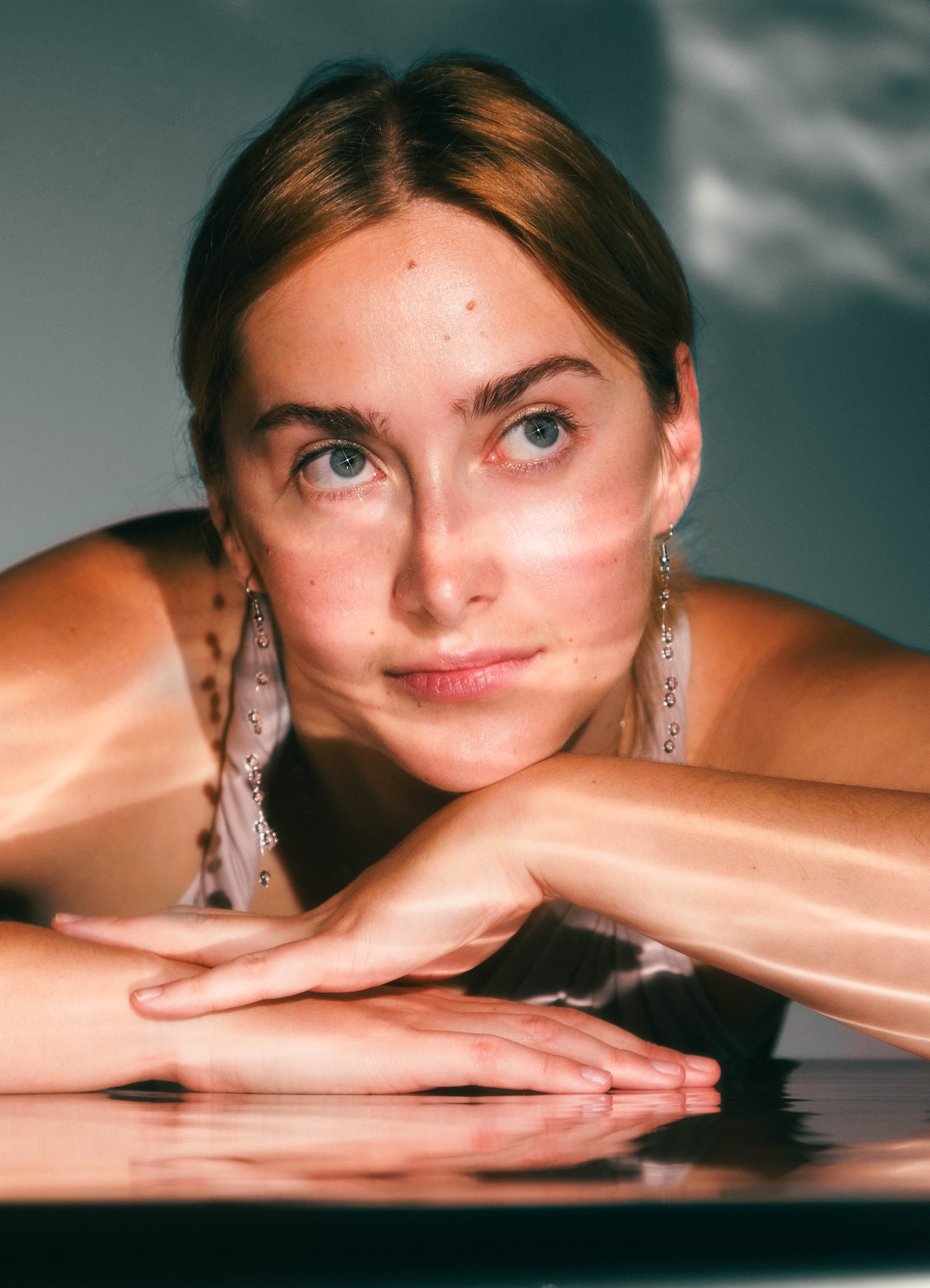 Editorial beauty portrait of a young woman with sparkles in her eyes for a skincare product.