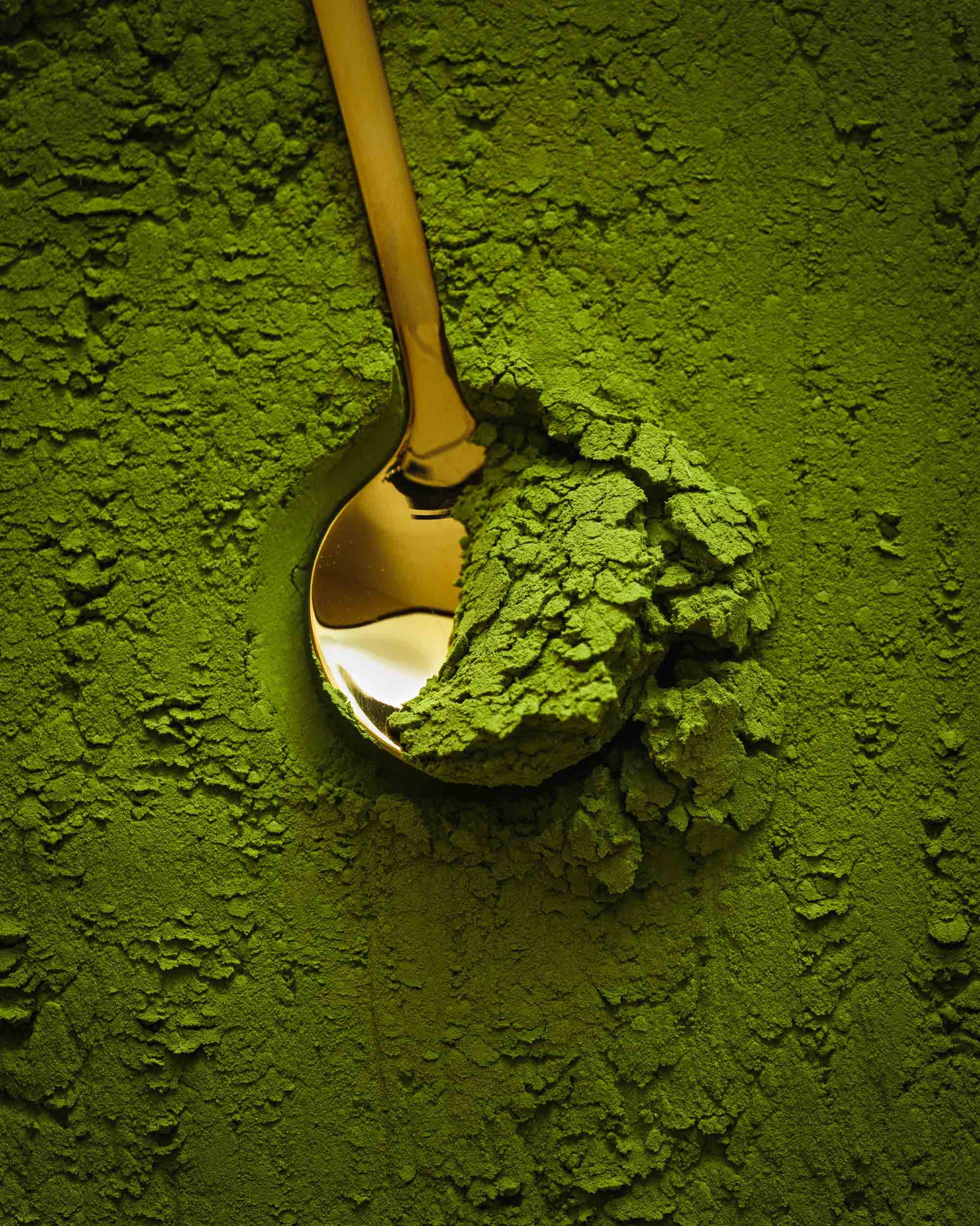 Commercial beverage product photo of matcha powder with a gold spoon.
