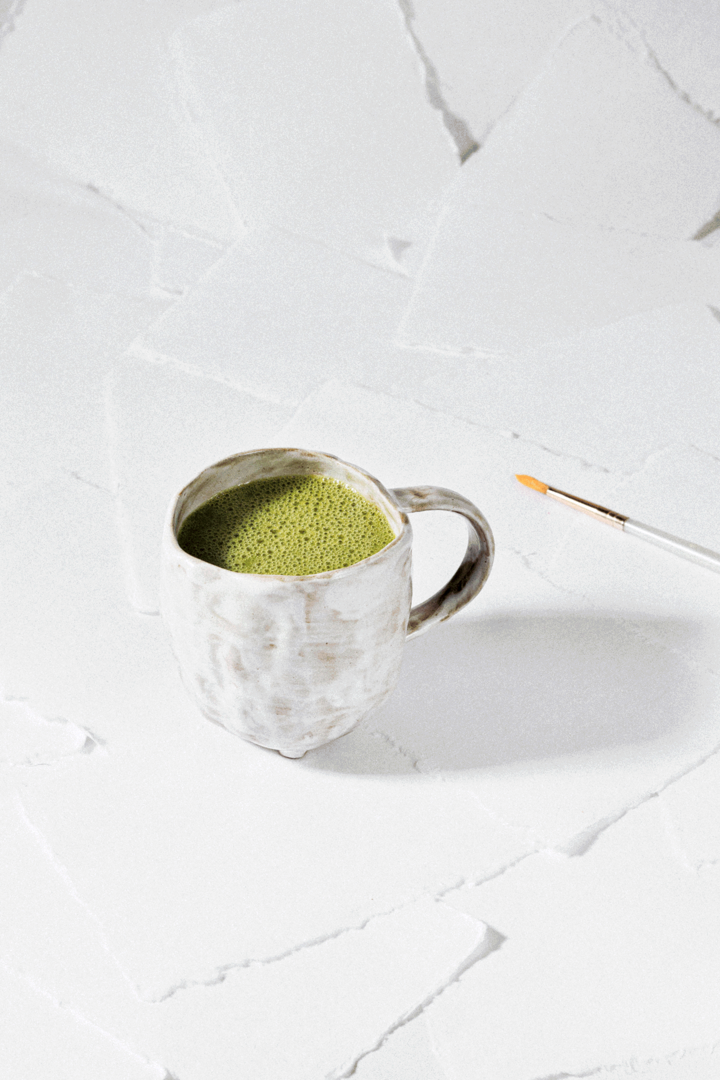 Playful commercial beverage gif of matcha on white watercolor paper.