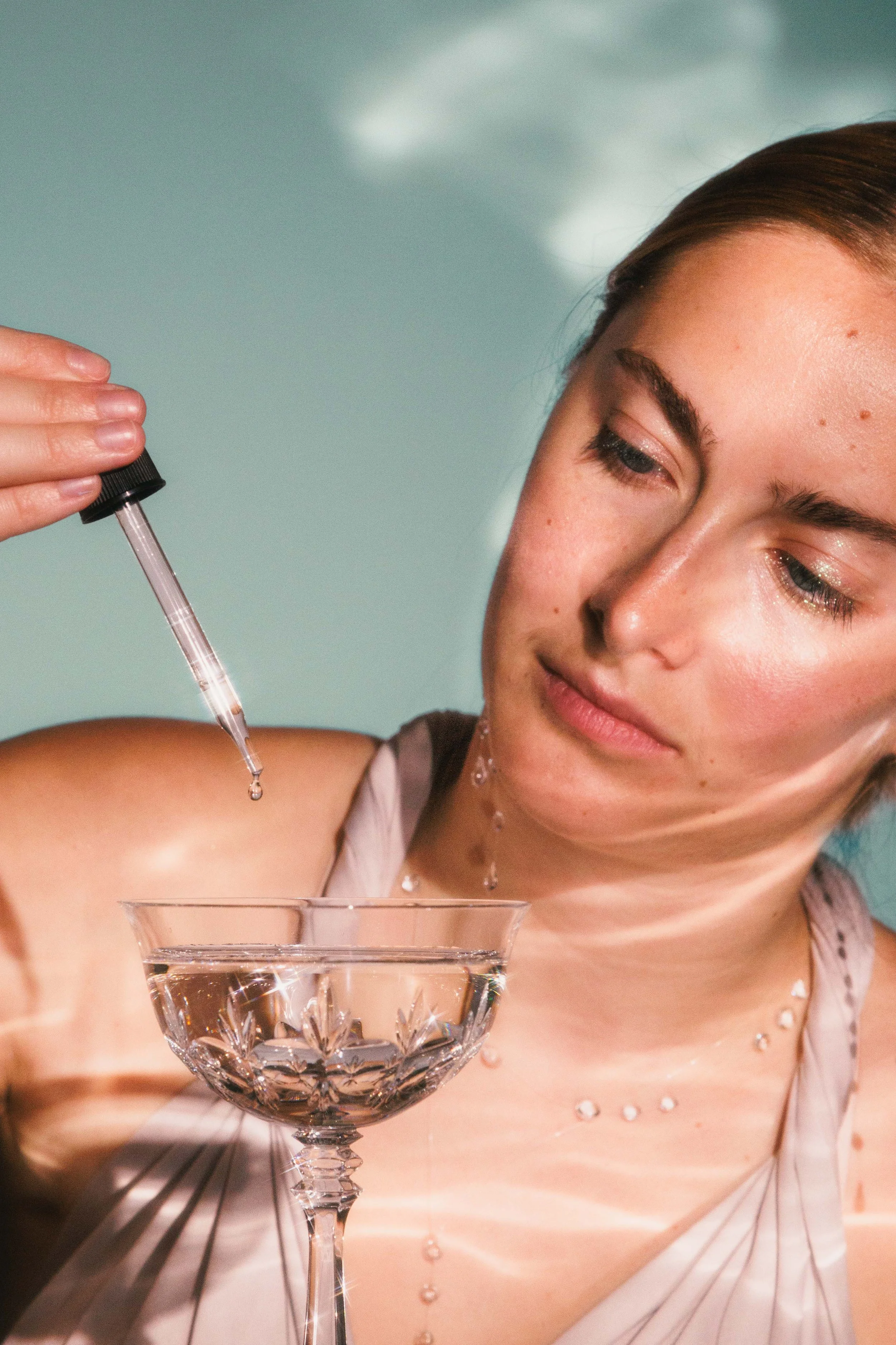 Editorial beauty photo of a woman playing with liquids and glassware.