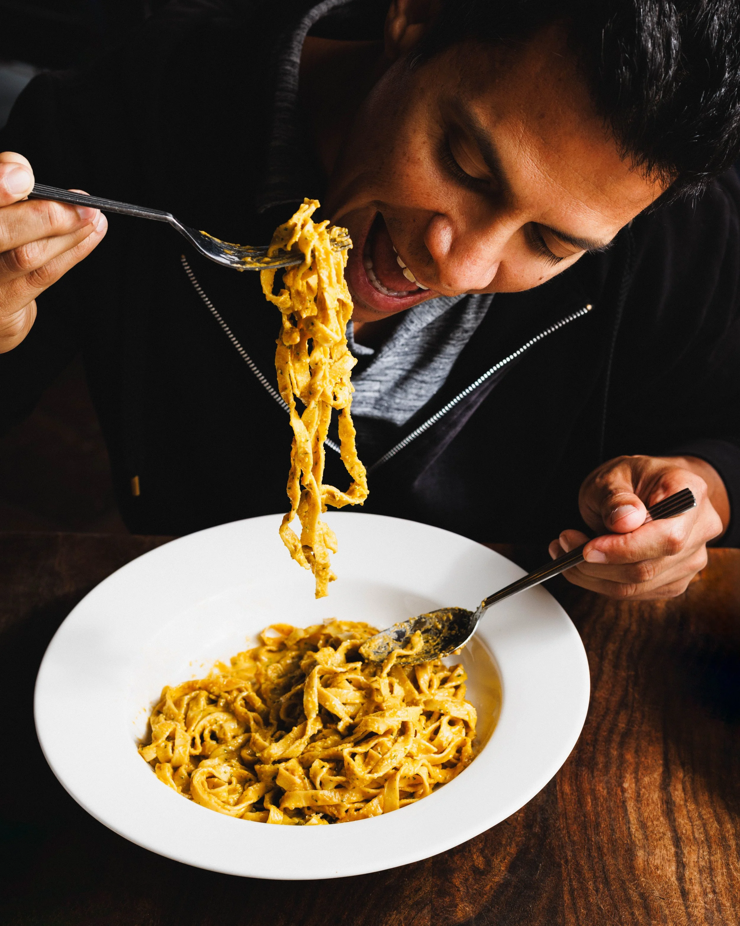 Commercial lifestyle portrait of a man eating pasta for a hospitality brand campaign.