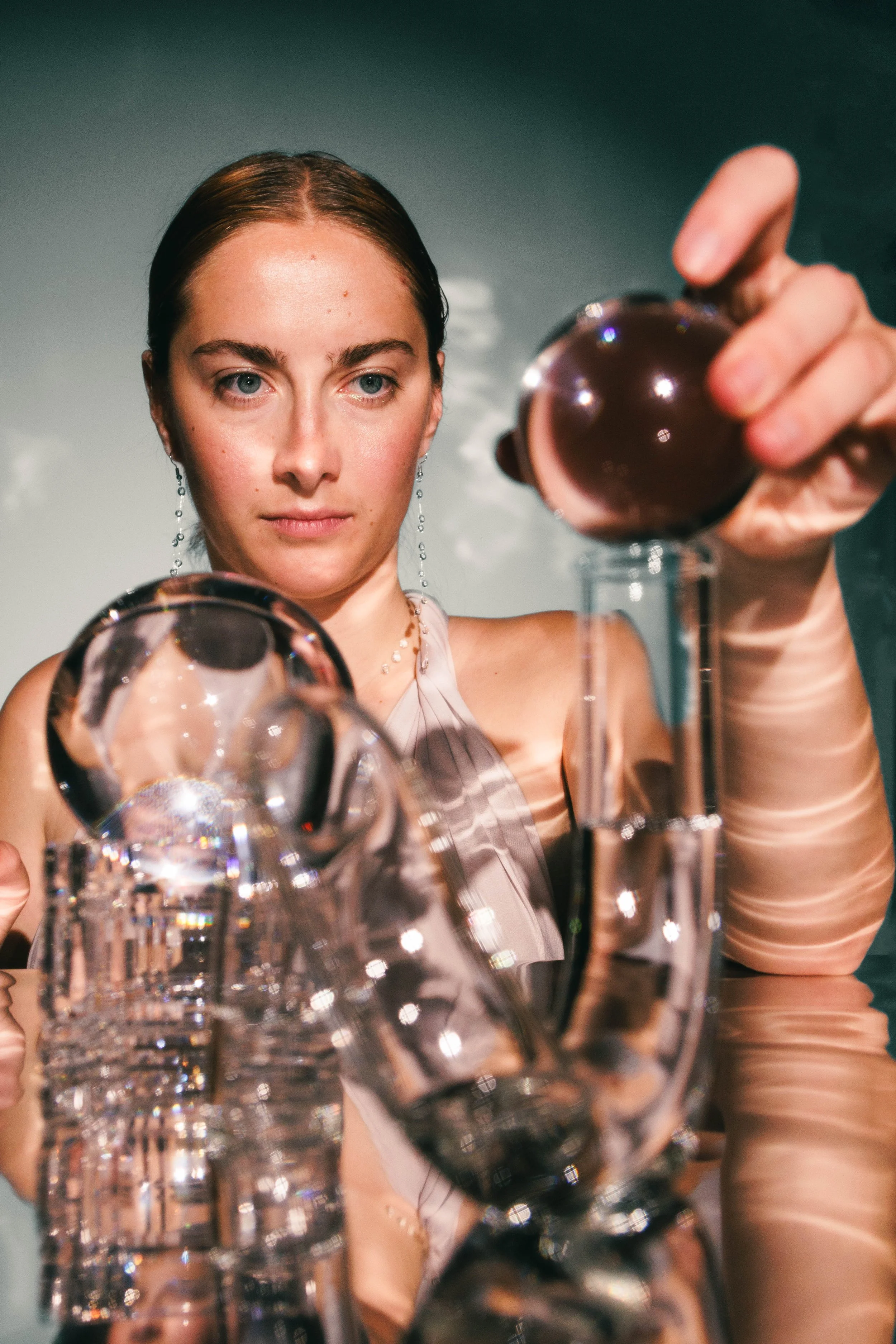 Conceptual beauty portrait of a woman playing with glass objects for an editorial project.