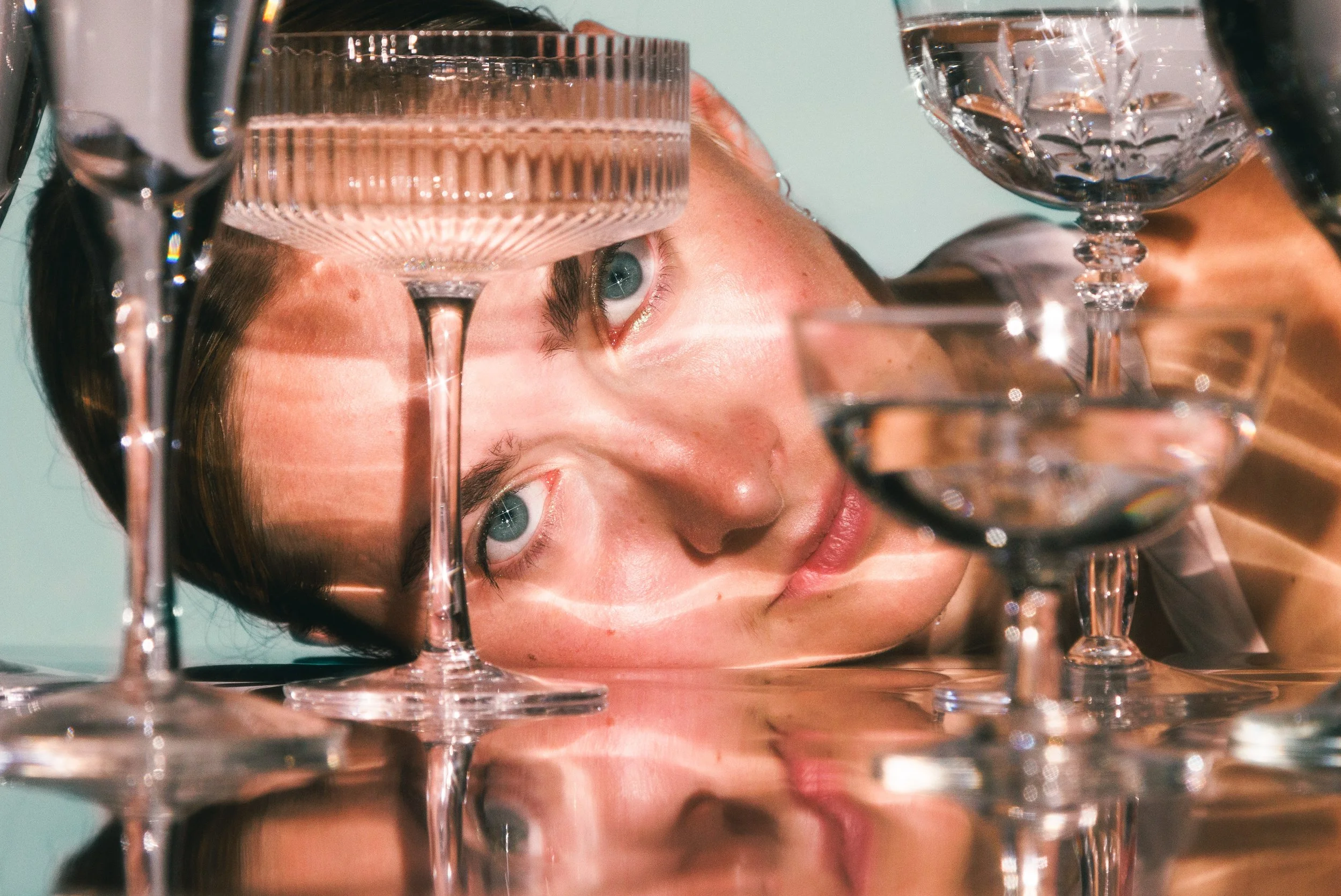 Commercial beauty portrait of a young woman with drinks and glassware.