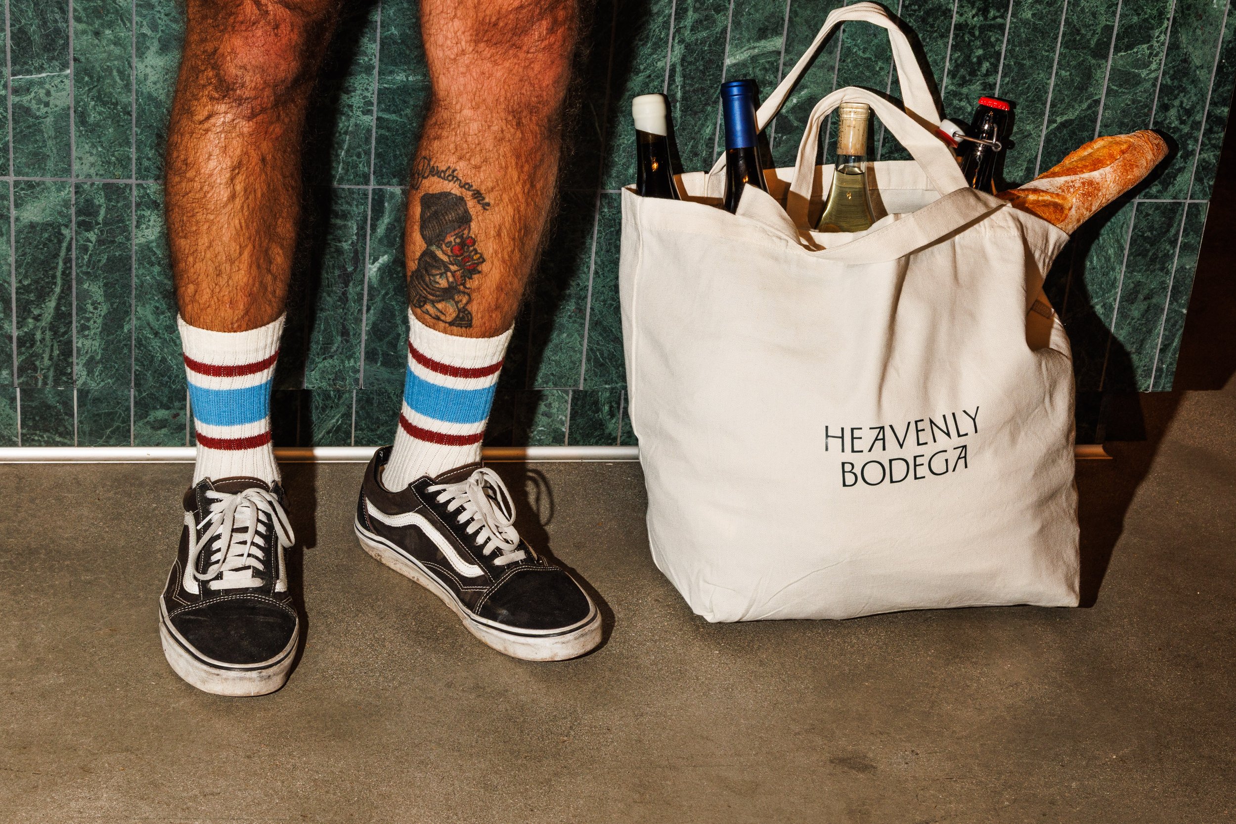Commercial lifestyle photo of a man's shoes with a bag full of wine and bread for a hospitality brand campaign in San Diego.