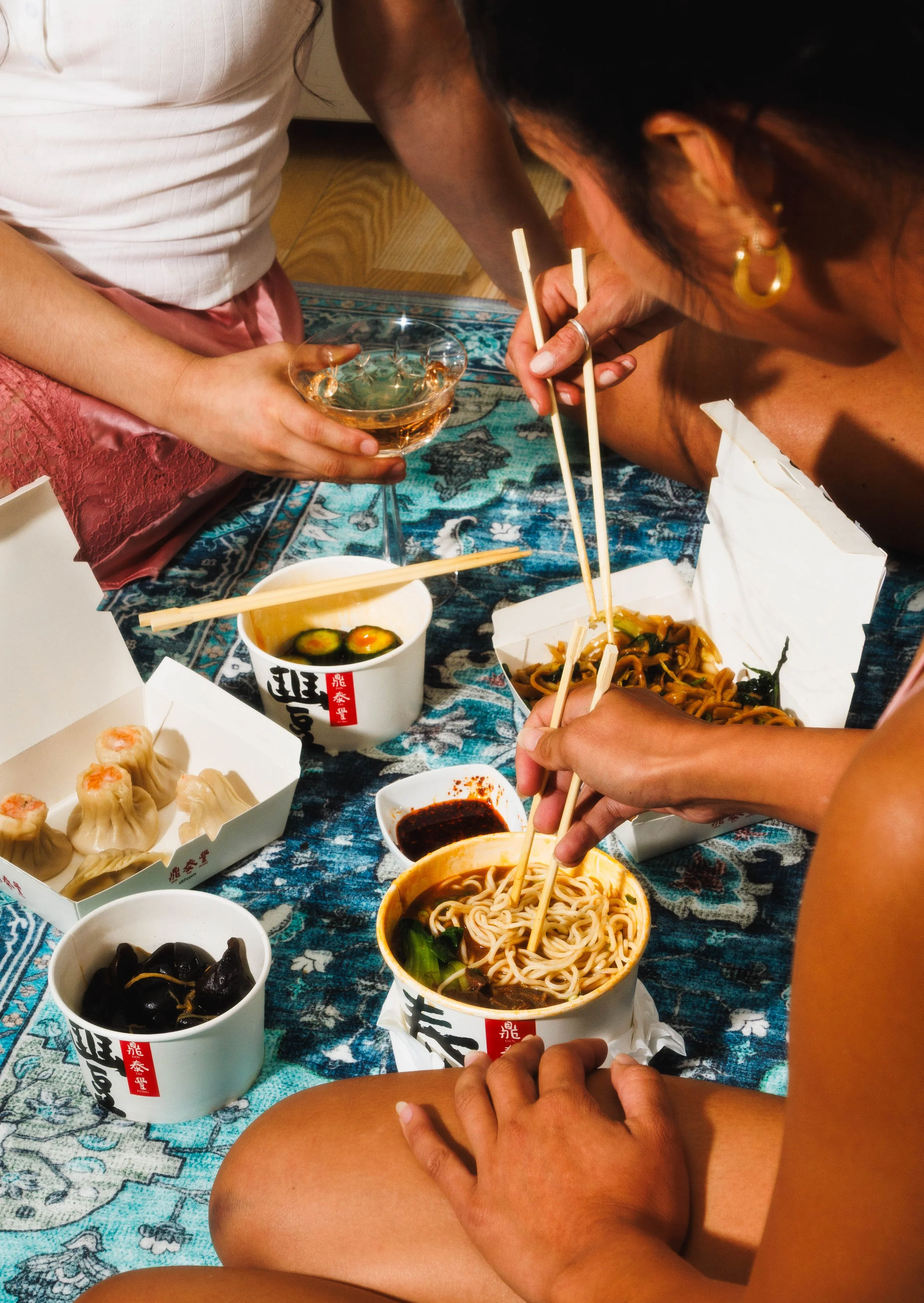 Commercial food photo of three women eating Chinese noodles on the floor for an advertising campaign.