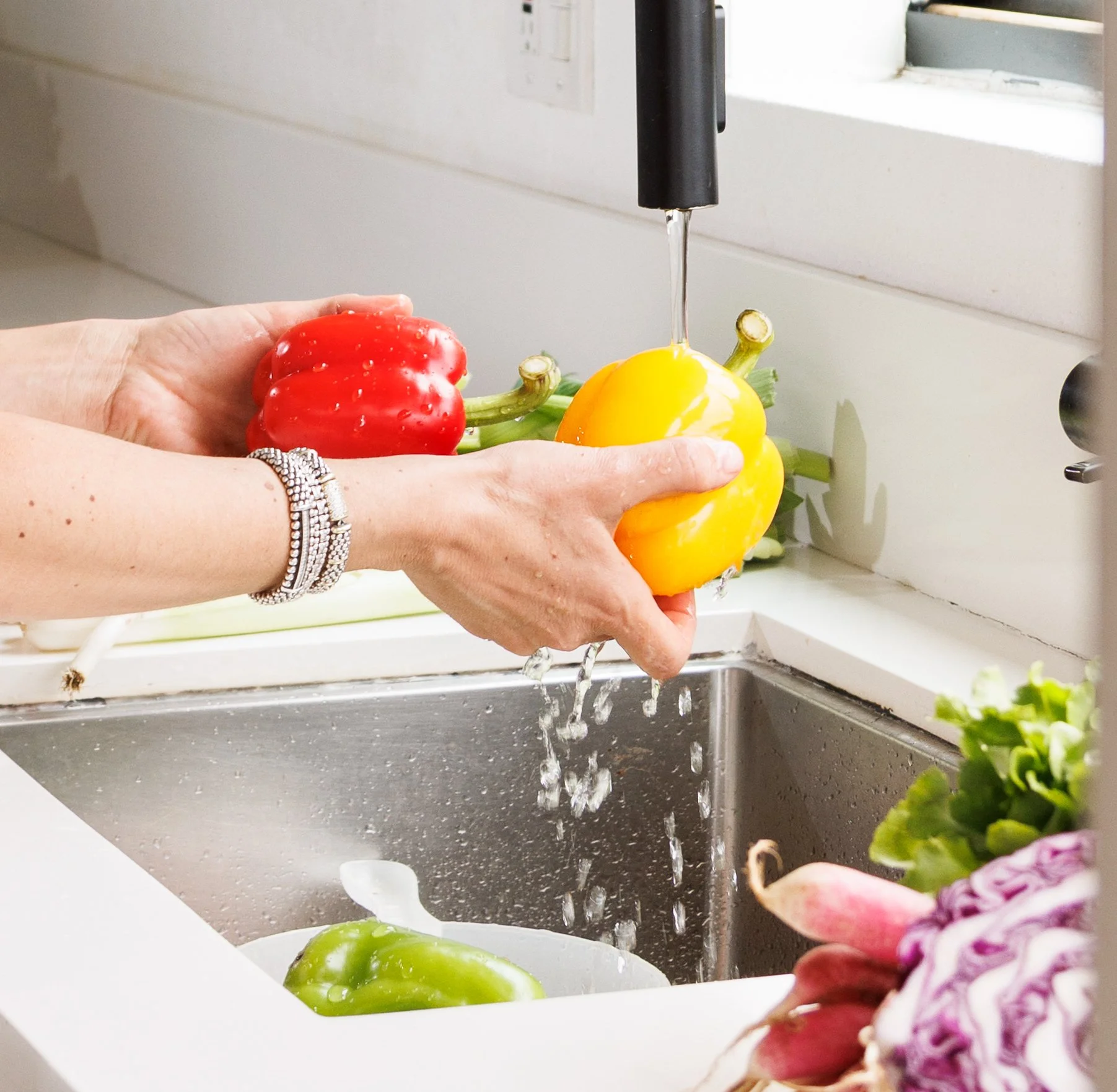 Editorial food photo of a woman washing peppers for a cookbook, by Amy Carson.