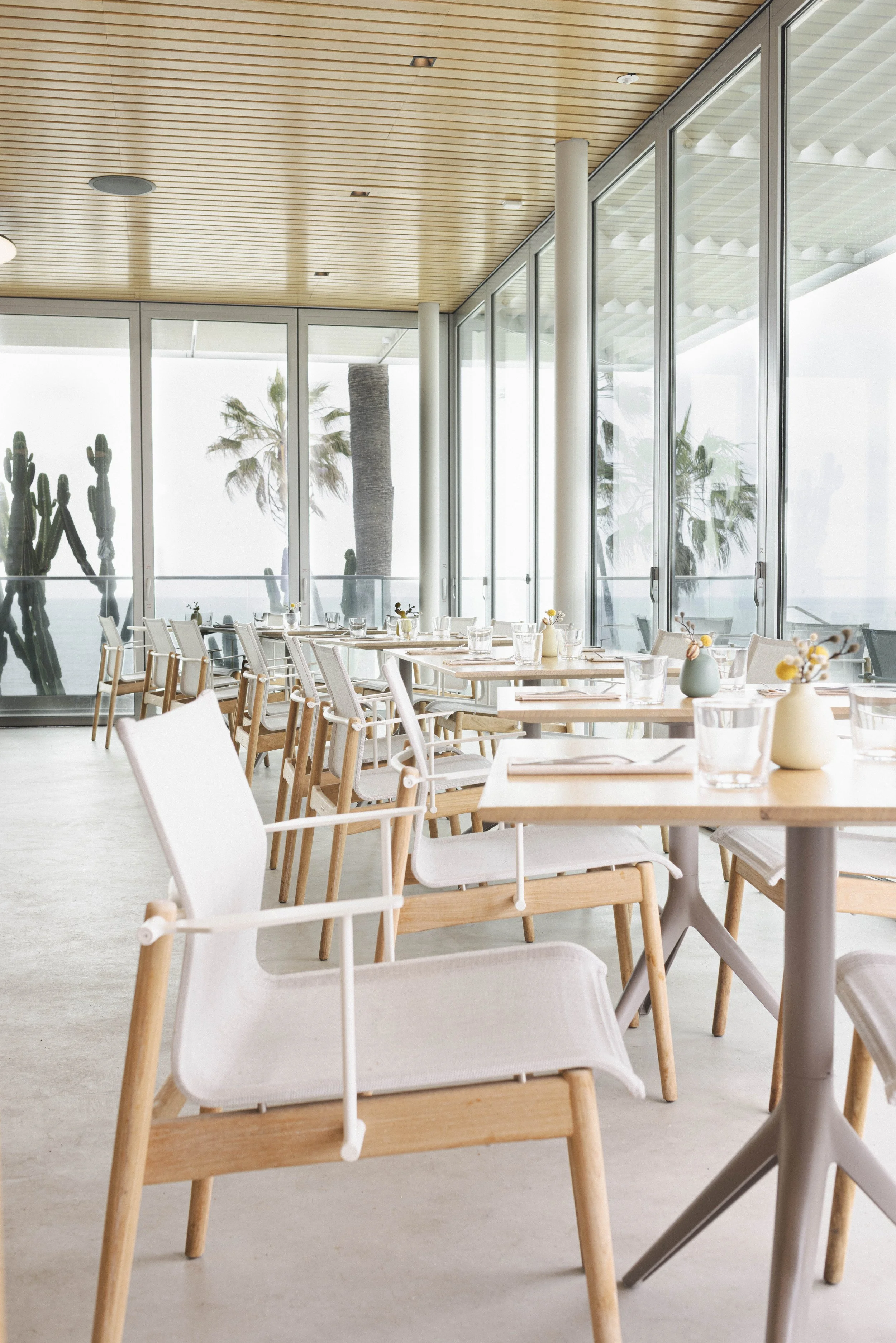 Commercial interiors and architectural photo of a restaurant dining room with palm trees and ocean in view in San Diego.