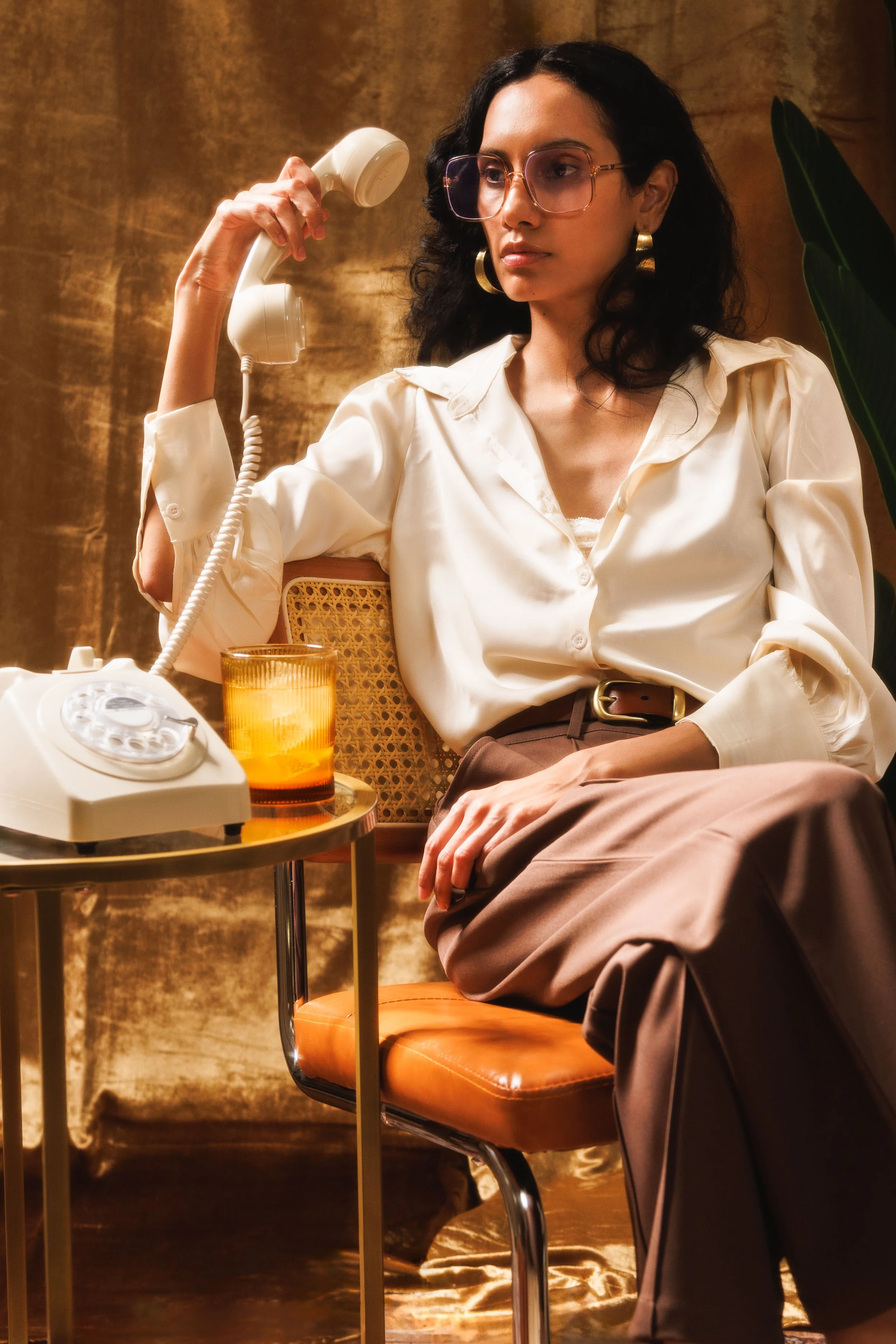Commercial lifestyle photo of a woman holding a rotary phone dressed in vintage style for a beverage brand.