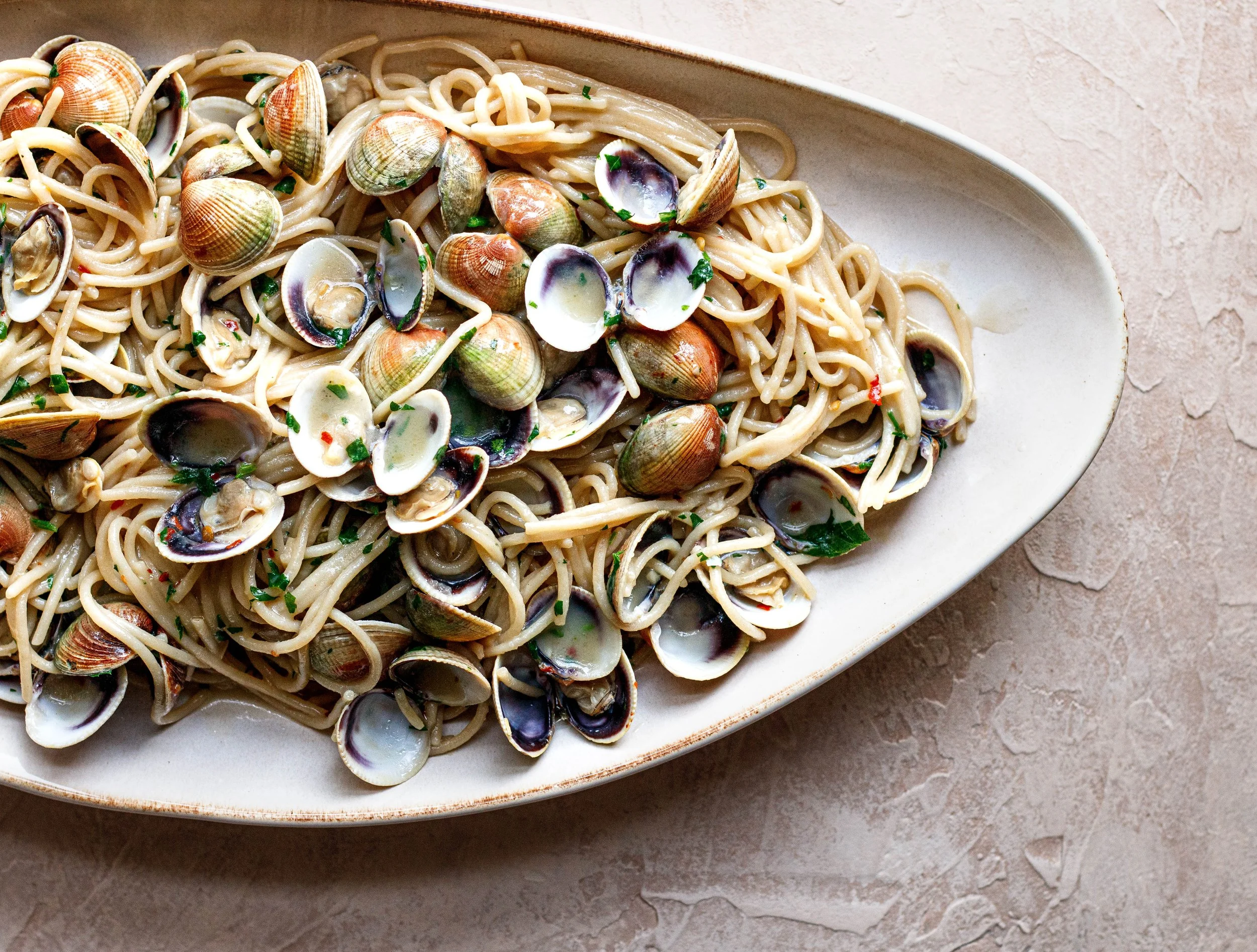 Editorial photo of spaghetti with clams on a plaster background, shot by Amy Carson.
