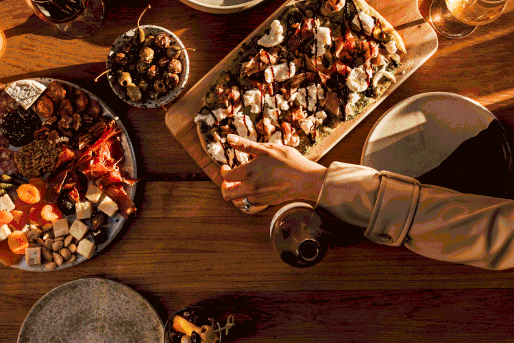 Commercial lifestyle gif of people passing plates of food and pouring wine for a hospitality advertising campaign.