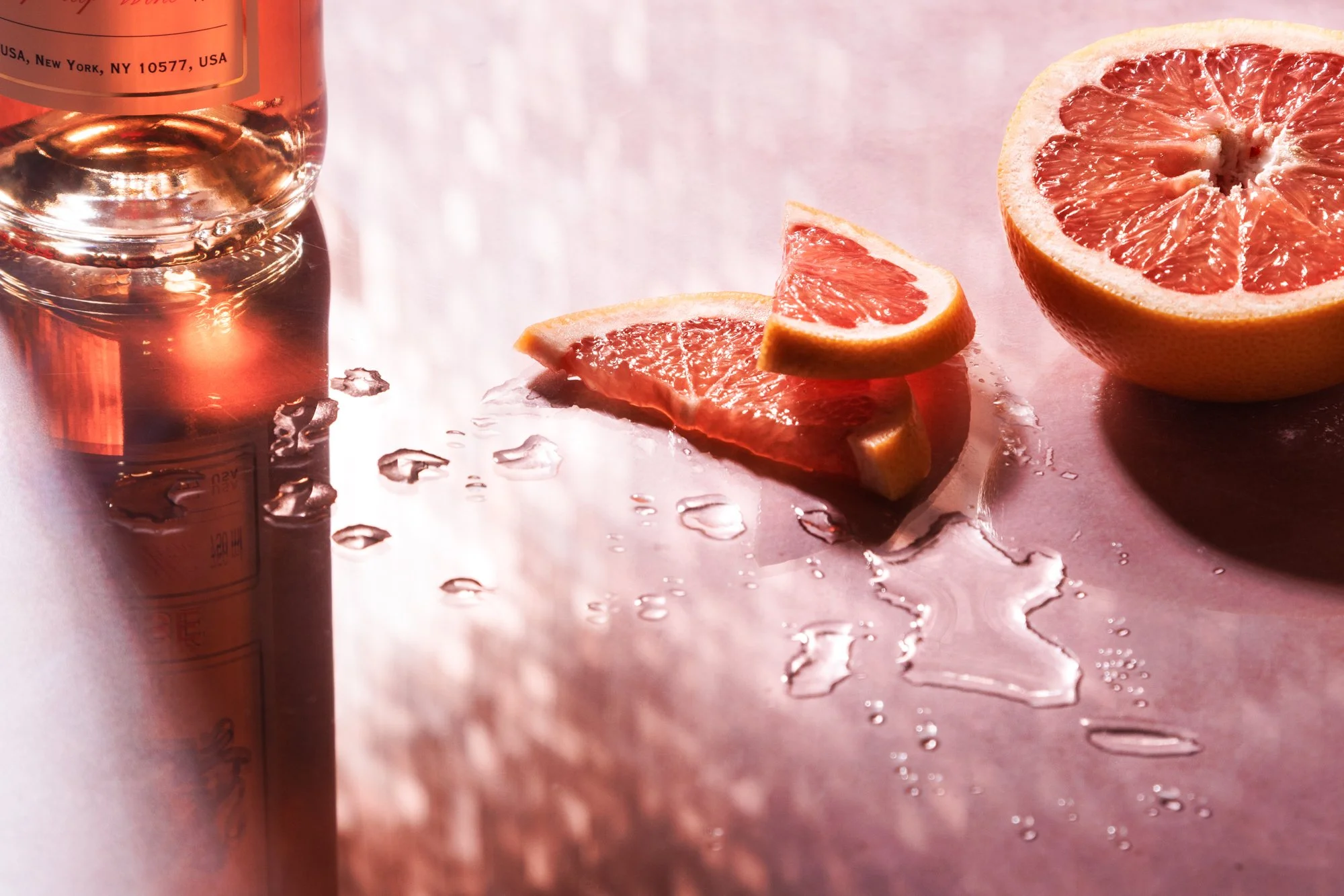 Commercial beverage still life photo of grapefruit and a wine bottle by Amy Carson.