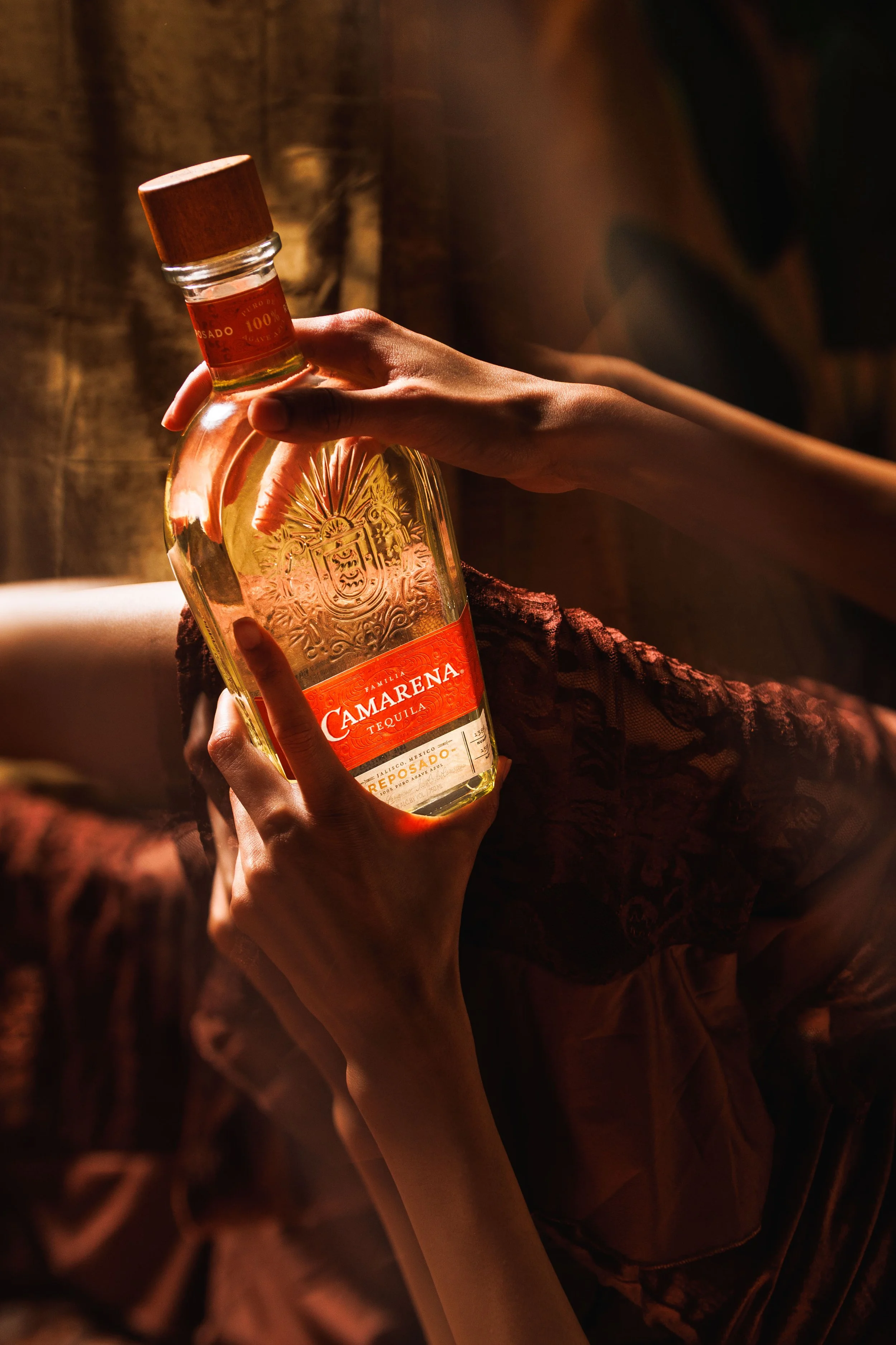 Commercial lifestyle product photo of a woman holding a tequila bottle with moody, cinematic lighting..