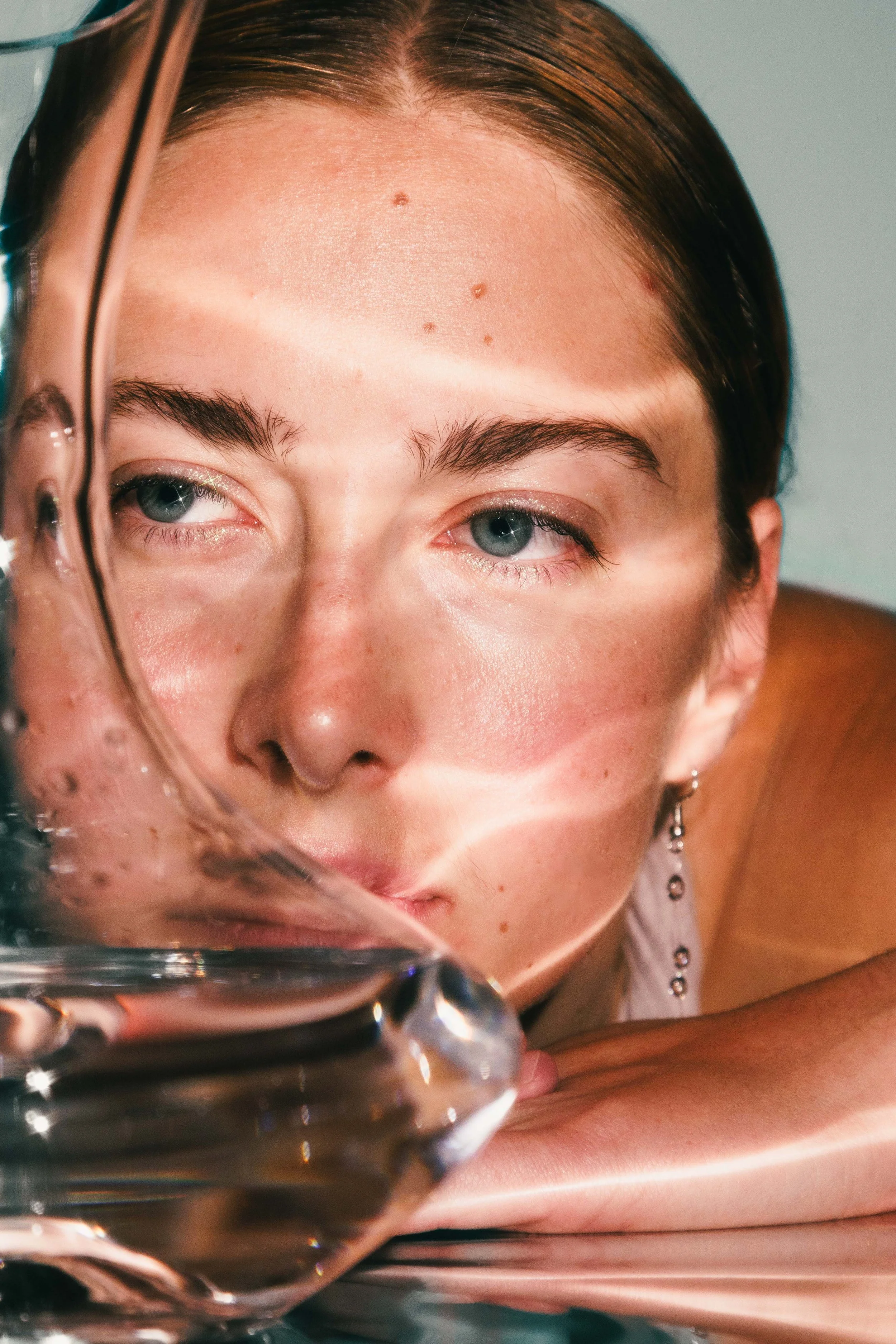 Conceptual beauty portrait of a woman looking through a glass vase for an editorial project.