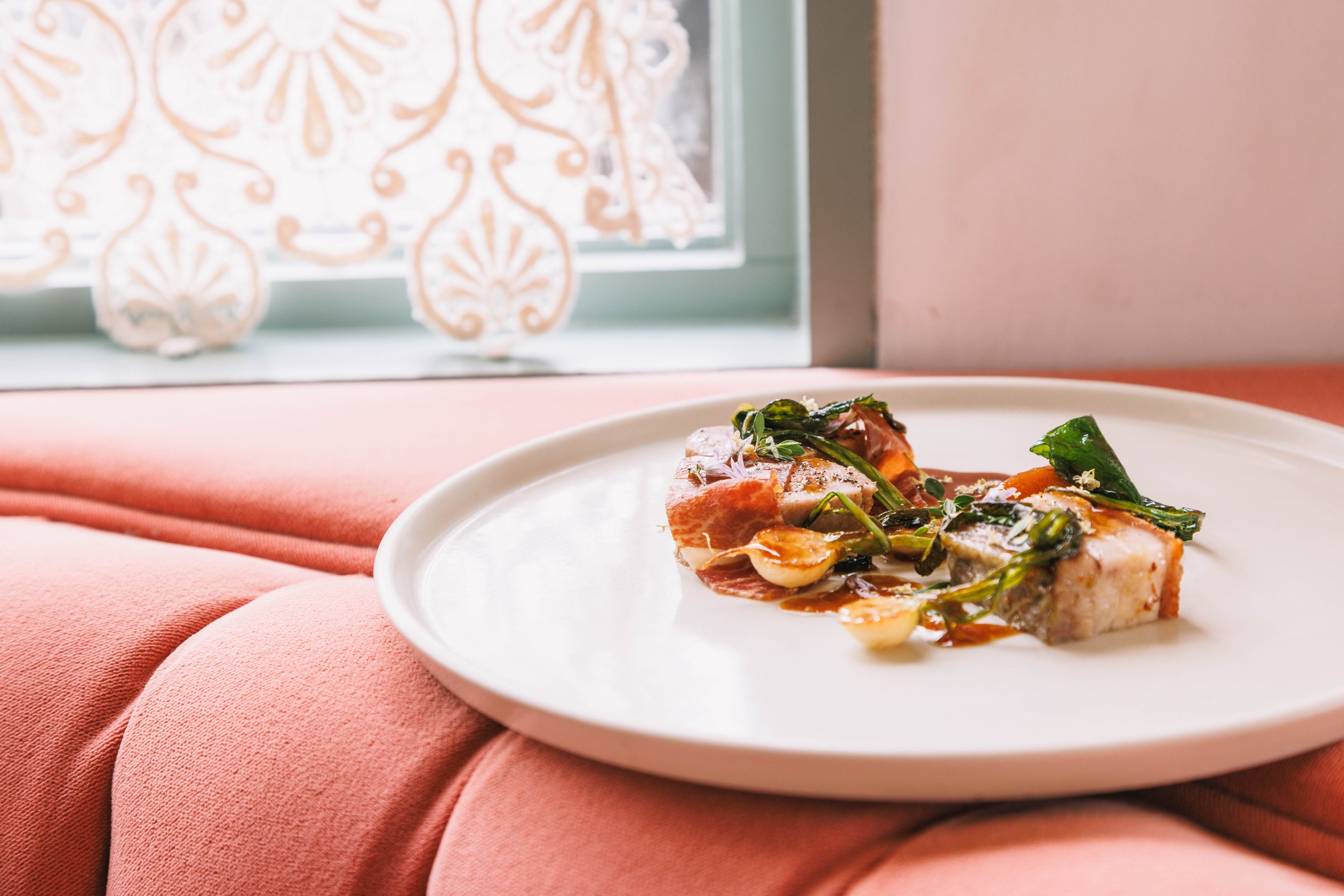 Editorial food photo of a plated dish on the back of a velvet booth.