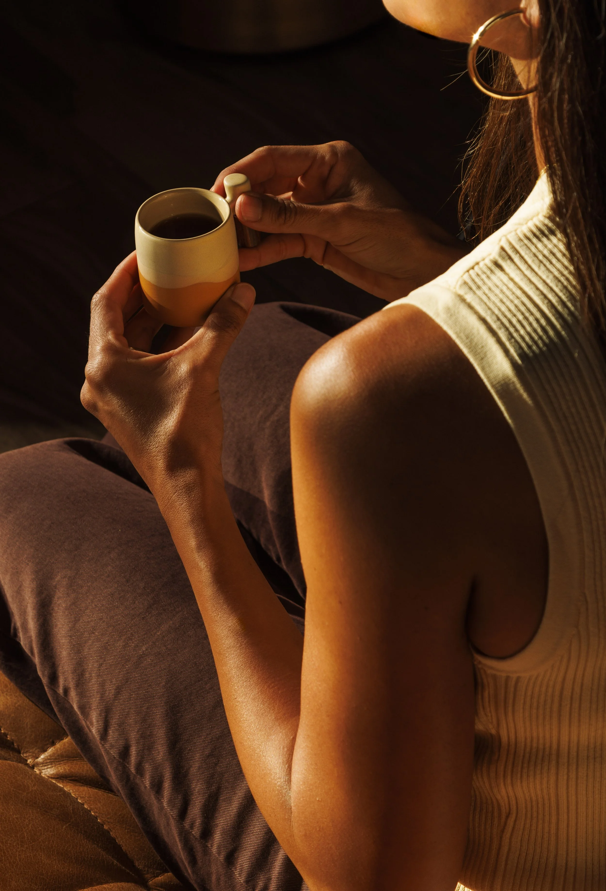 Commercial lifestyle photo of a woman drinking coffee with cinematic golden light.