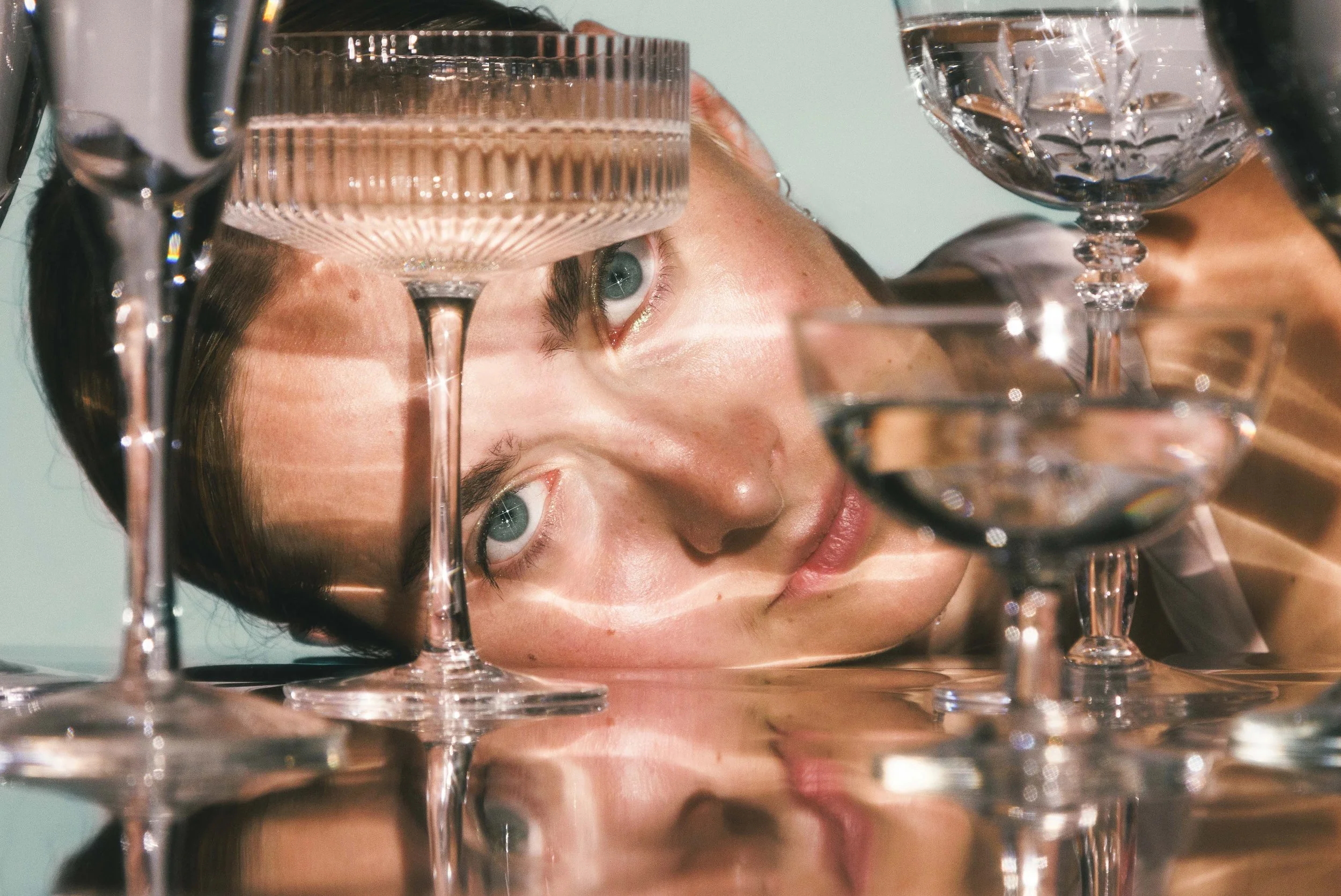 Editorial beauty photo of a young woman with glassware and reflective objects for an editorial.