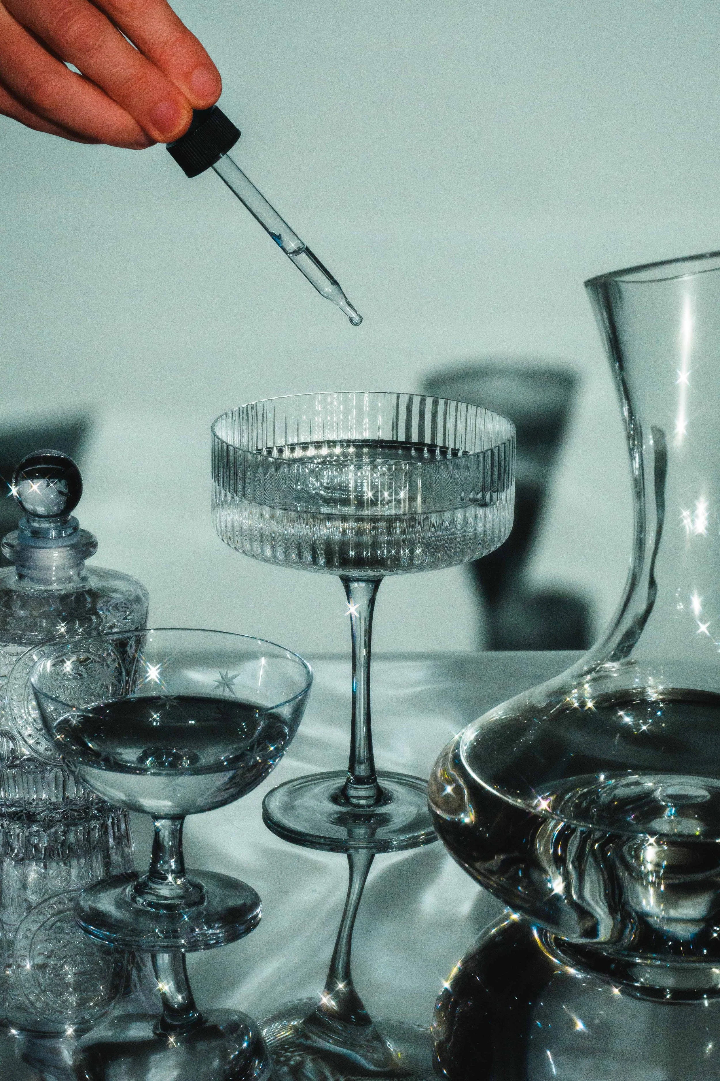 Conceptual editorial still life of liquids, glassware, and reflections.