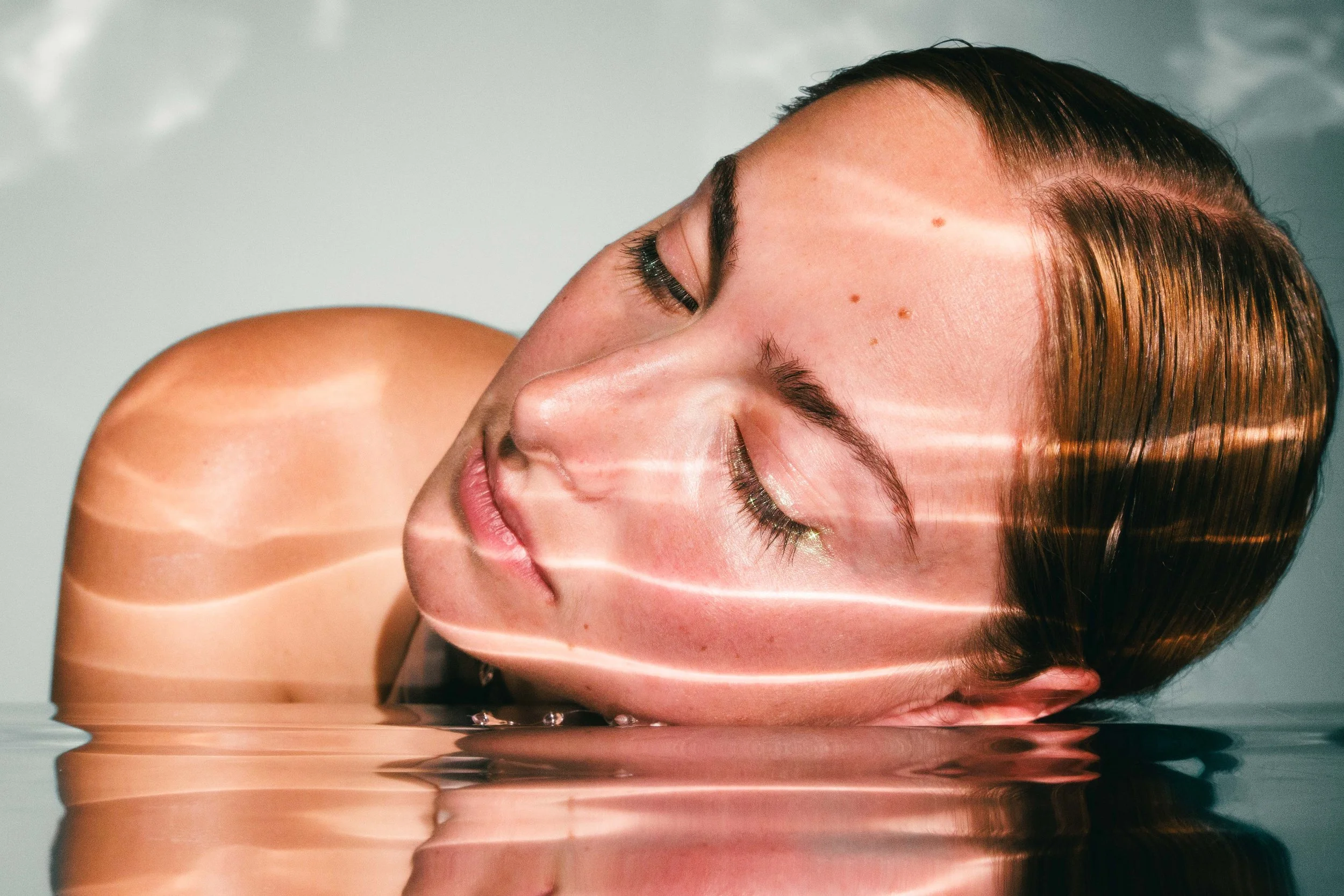 Conceptual beauty portrait of a young woman with reflective surfaces and glowing skin.